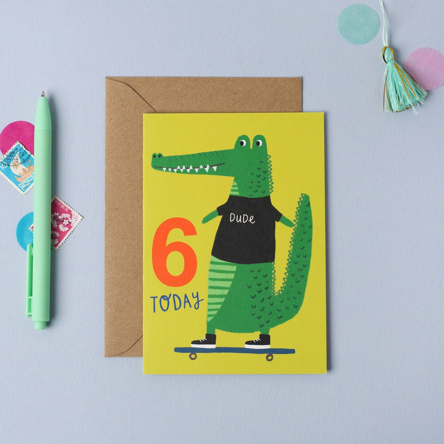 Yellow card with a friendly crocodile in a t-shirt riding a skateboard, with “6 Today” text.