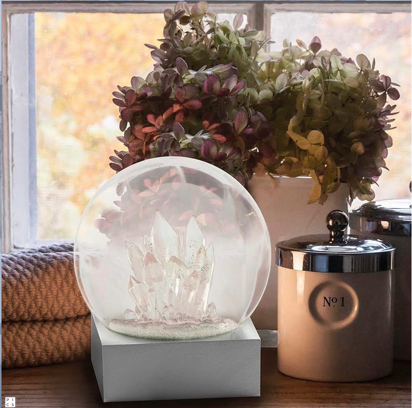 A crystal snow globe with a rose quartz look, set on a silver base.