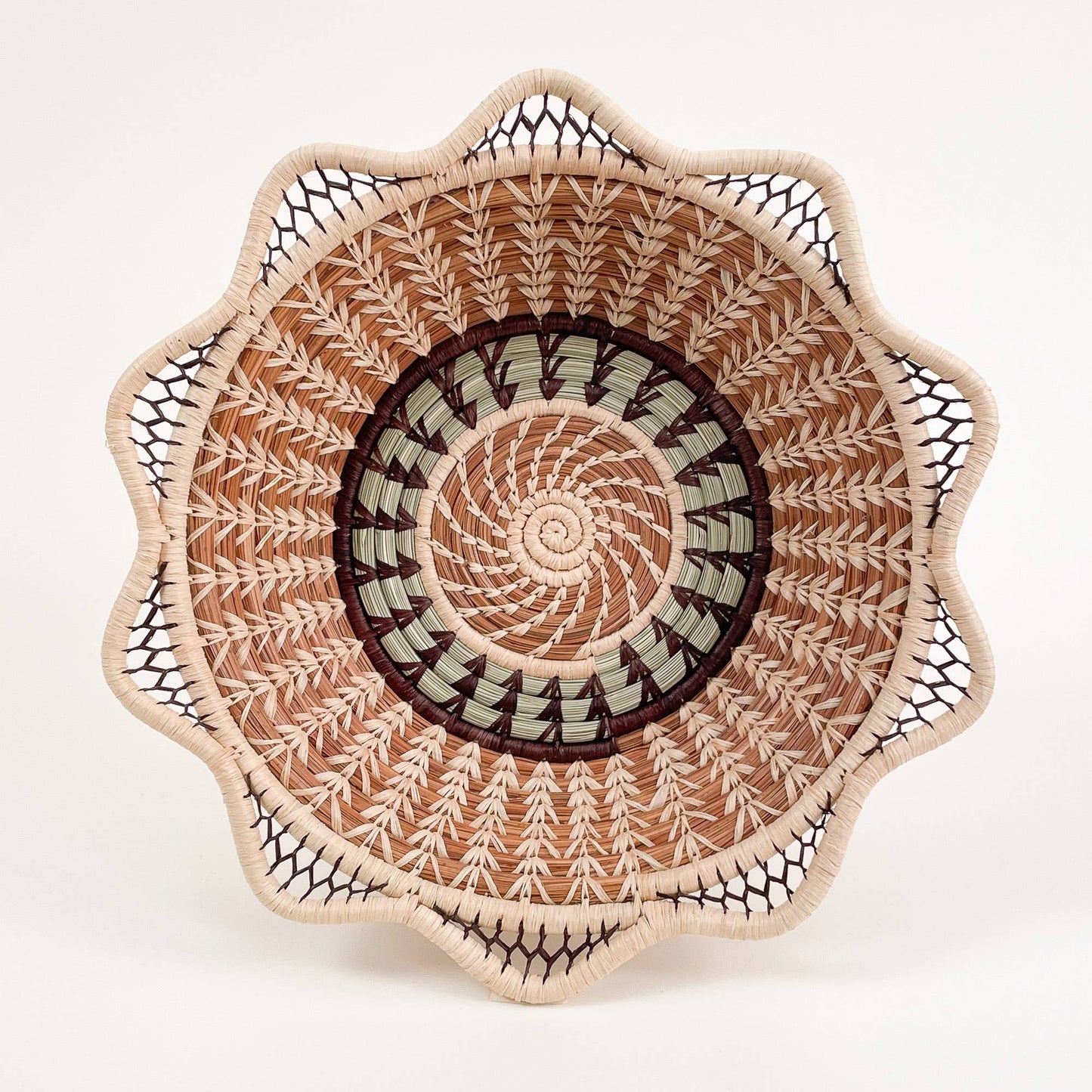 Handwoven basket with spiral and scalloped edge design in natural tones