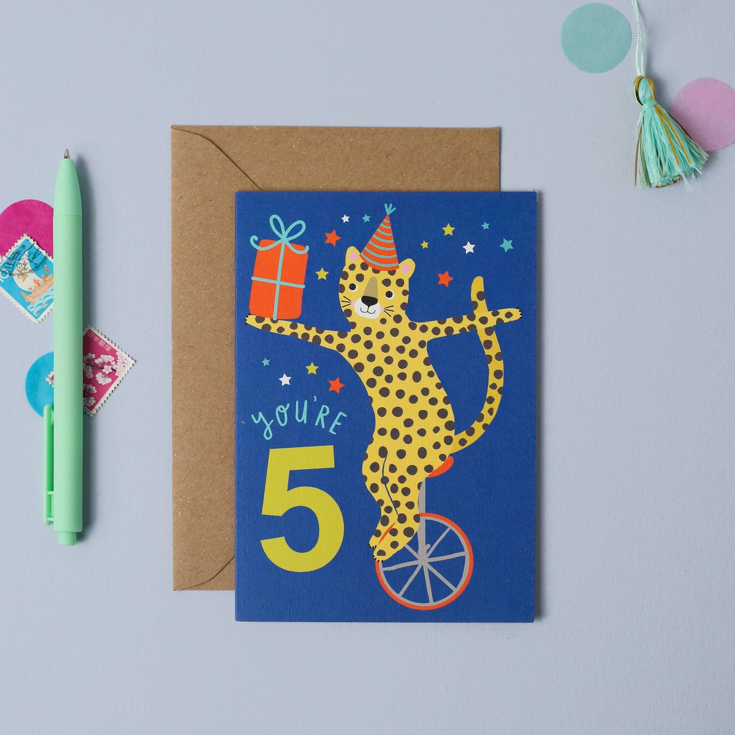 Blue card featuring a spotted leopard on a unicycle, holding a gift and wearing a party hat, with “You're 5” text.