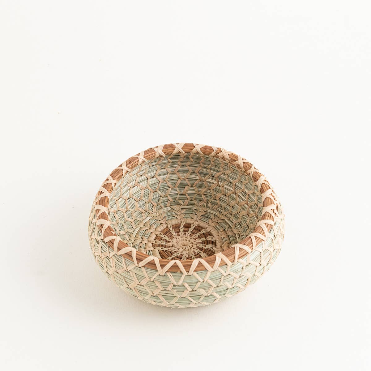 Handwoven desk basket with pine needle trim, featuring a natural, light green and brown pattern.