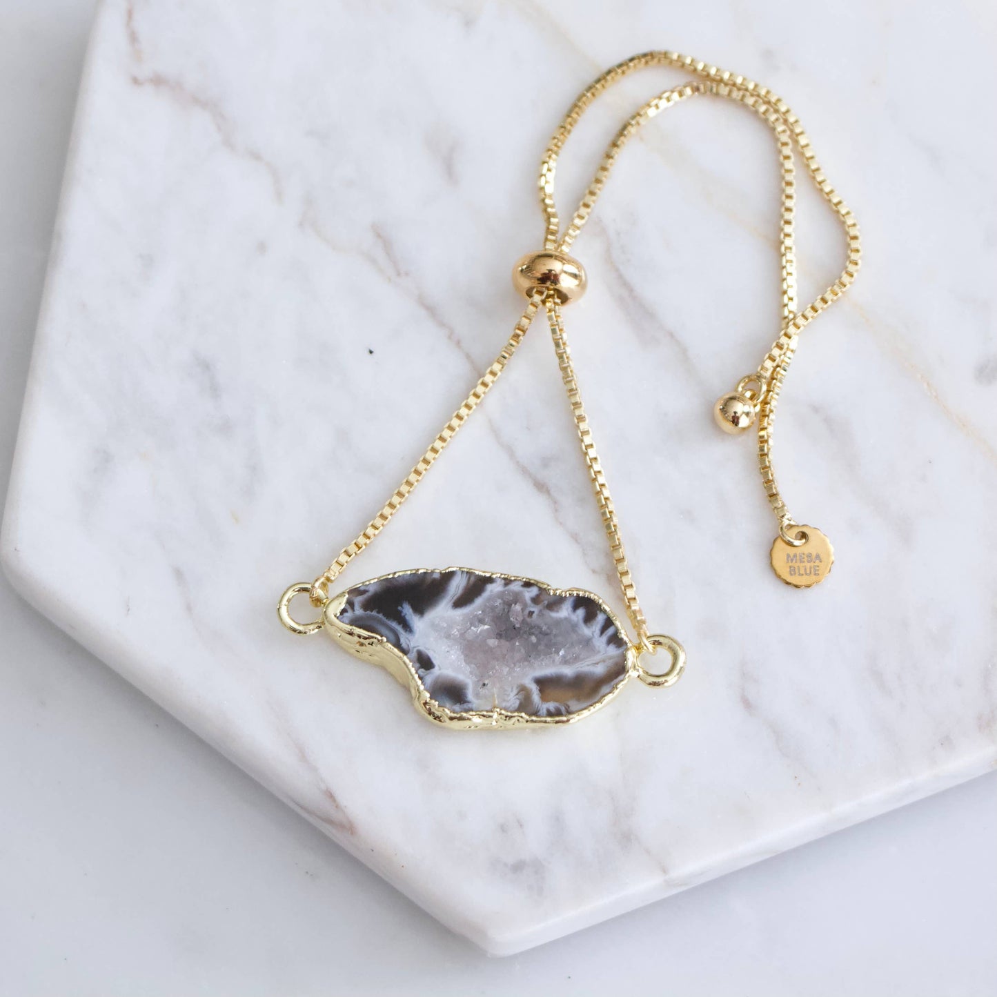 Gold-plated adjustable bracelet featuring a unique geode slice pendant with intricate natural patterns.