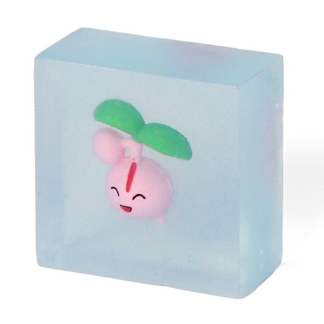Handmade light blue soap bar featuring a cute pink character with green leaves inside.
