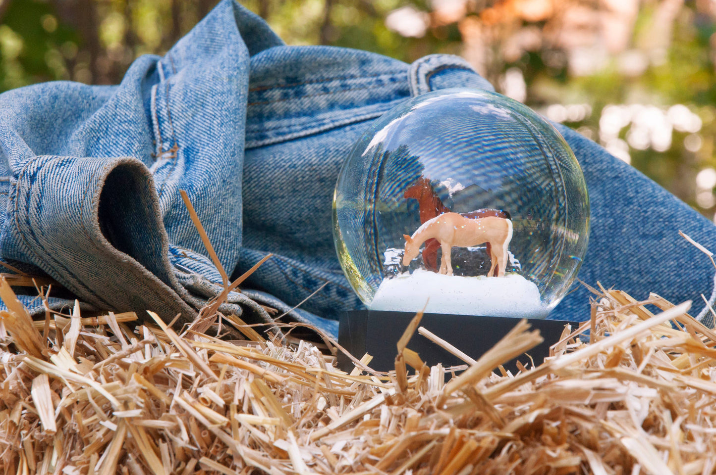 A clear snow globe with a horse inside, set on an iconic black base, capturing a charming winter scene.