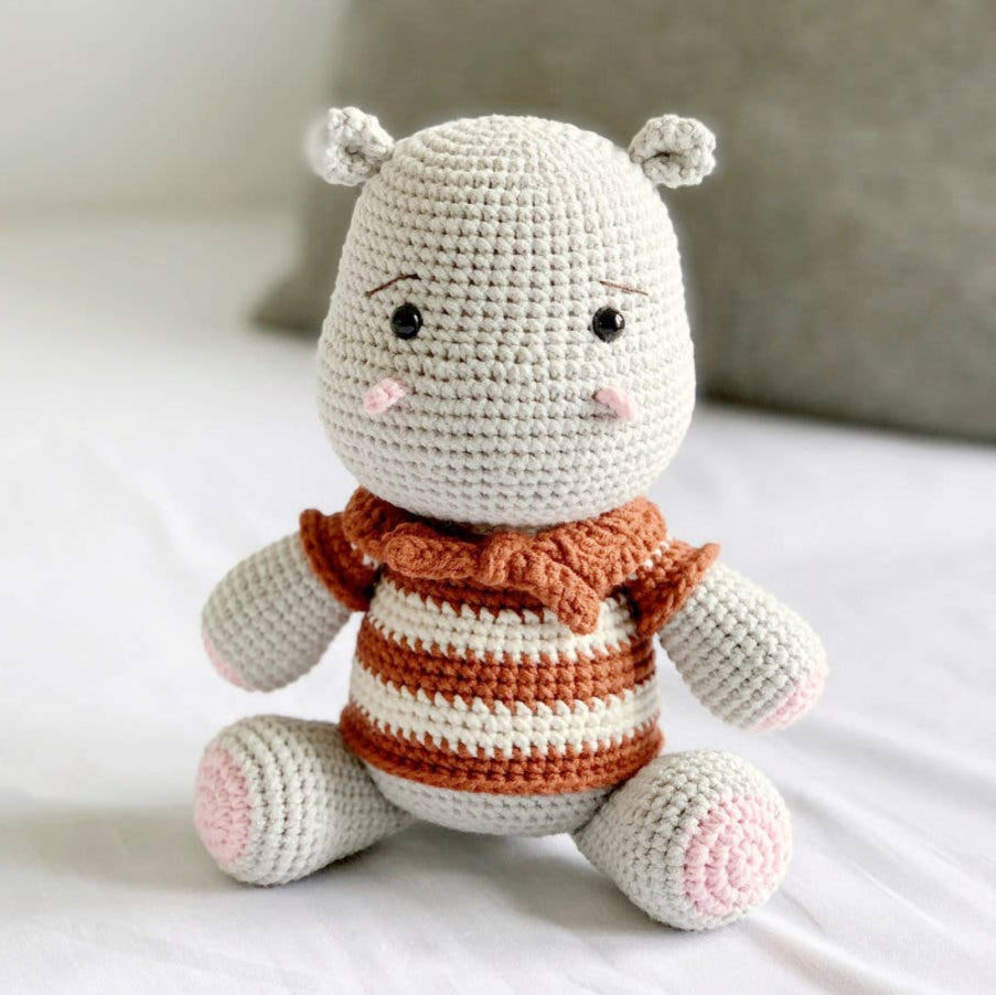 Crocheted hippo plush toy with striped sweater and blushed cheeks