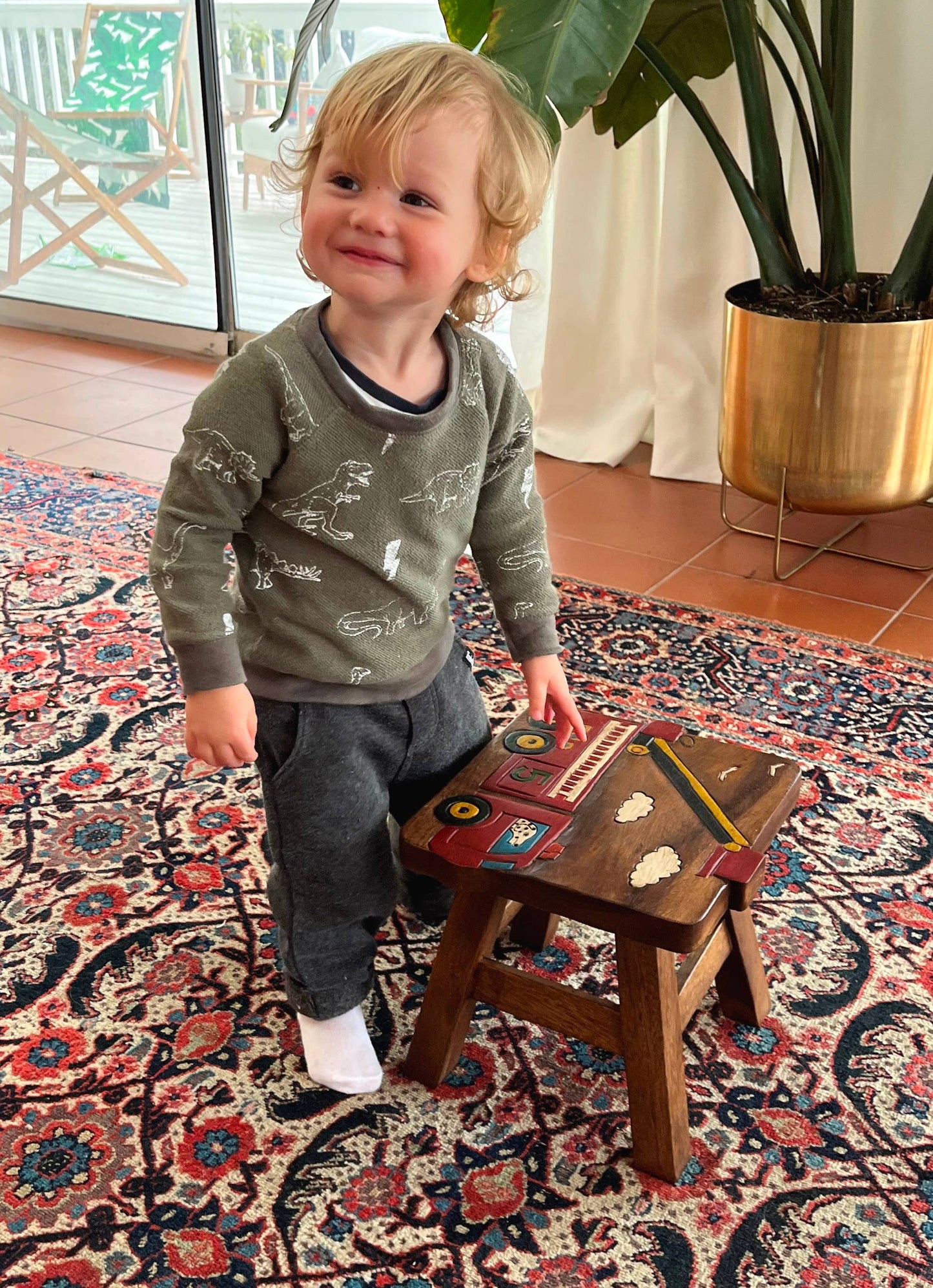 Wooden stool with a colorful fire truck carving, perfect for kids' rooms.