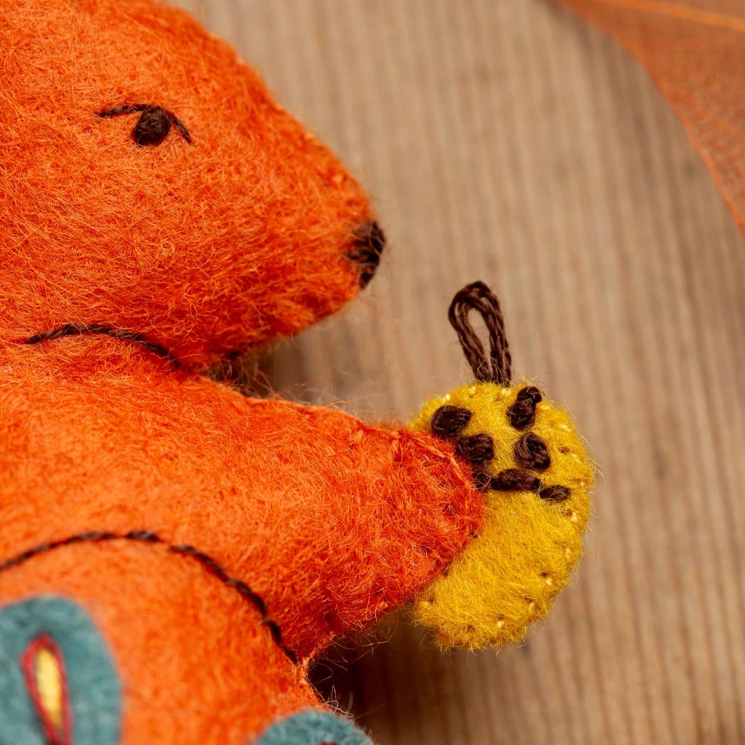 Handmade felt squirrel kit with orange body, yellow paws, and brown details for crafting.