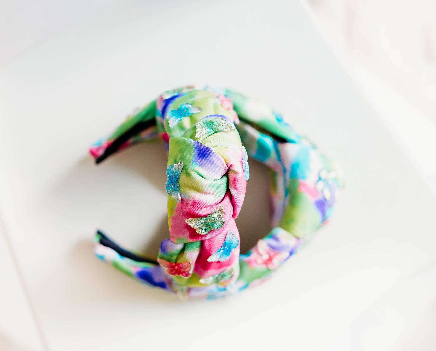 A colorful beaded headband with butterfly embellishments in a rainbow watercolor design.