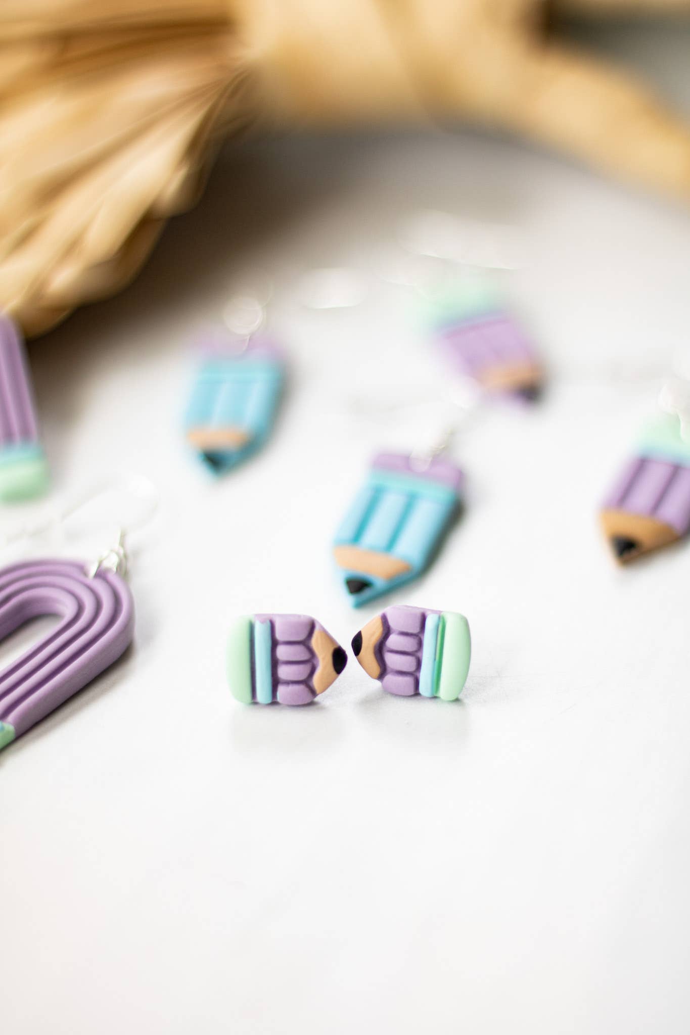 Blue pastel pencil-shaped dangle earrings with purple and green accents, perfect for a unique gift.