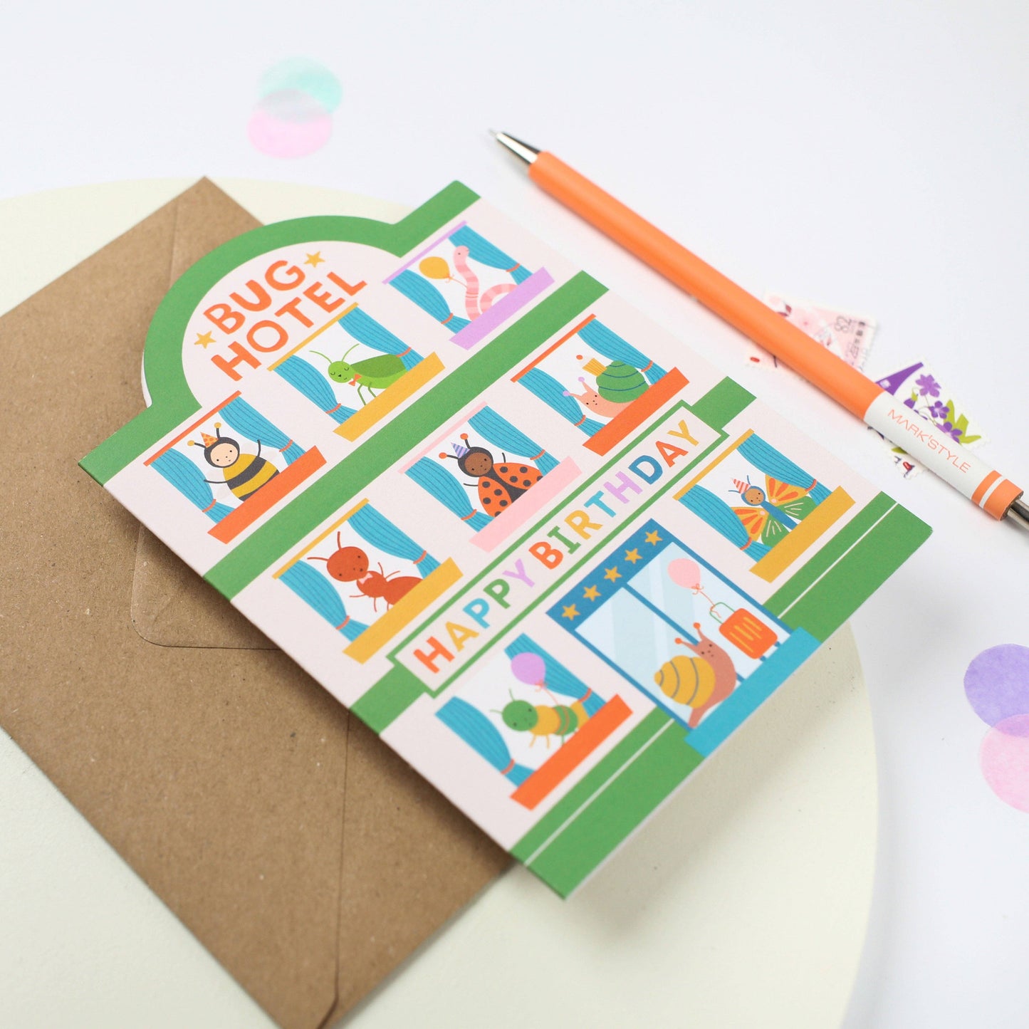 A colorful die-cut birthday card featuring a "Bug Hotel" design with cute insect illustrations and the text "Happy Birthday."