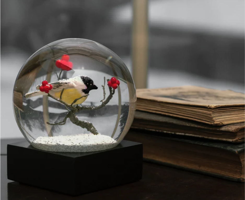 Cardinal singing snow globe with a black base, featuring a red bird perched on a snowy branch with berries.