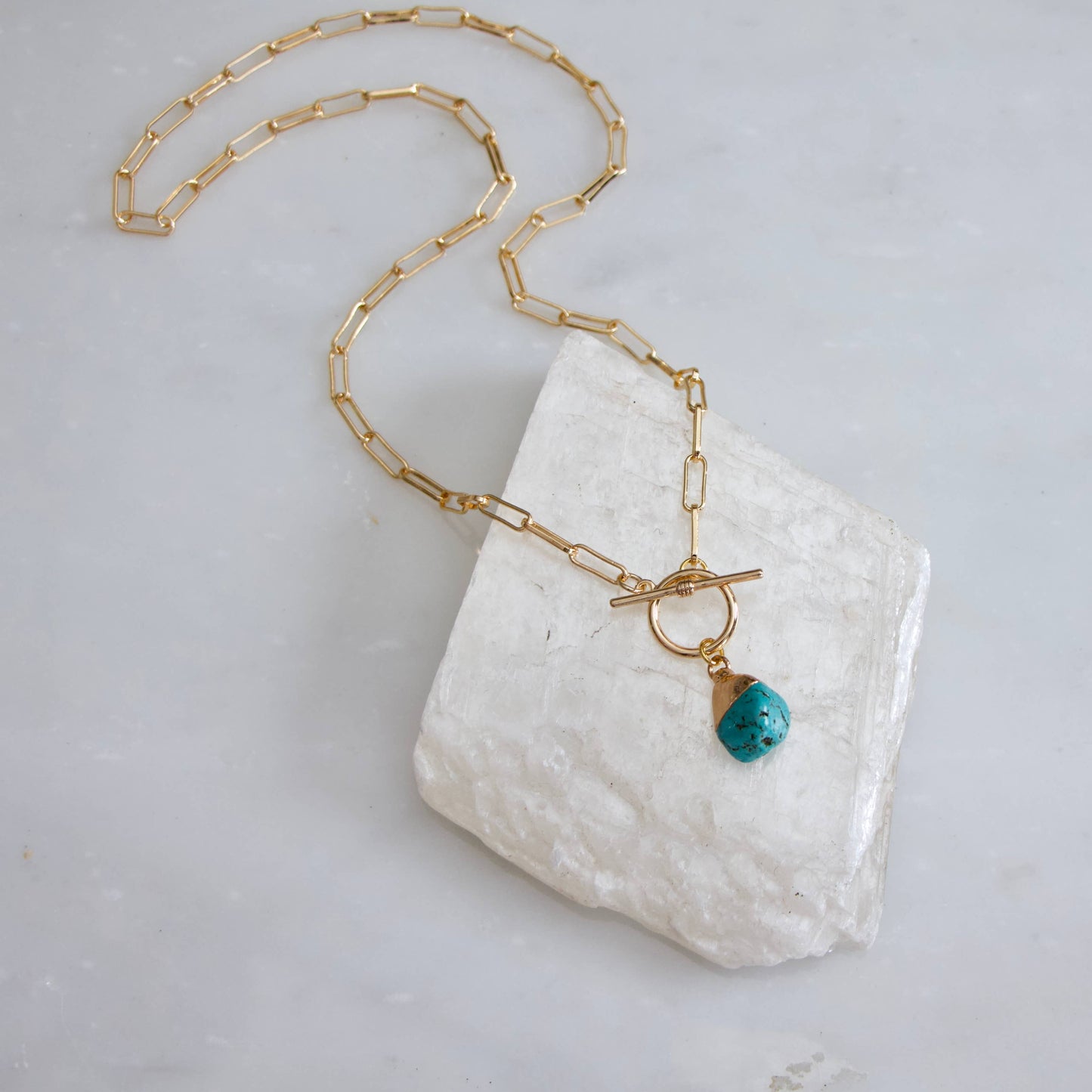 Gold paperclip chain necklace featuring a turquoise nugget pendant and a toggle clasp.