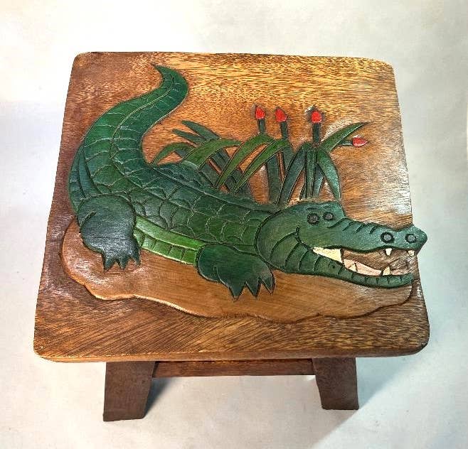 Hand-carved wooden stool with a green alligator design