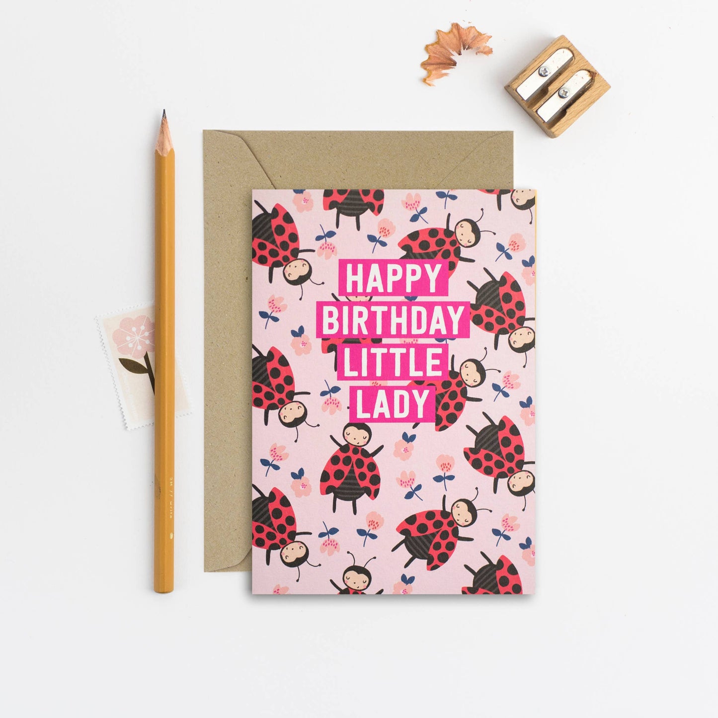 Illustrated birthday card with ladybugs on a pink background and gold foil accents