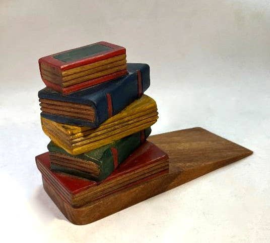 Hand-carved wooden doorstop shaped like a stack of vintage books in red, blue, and green.