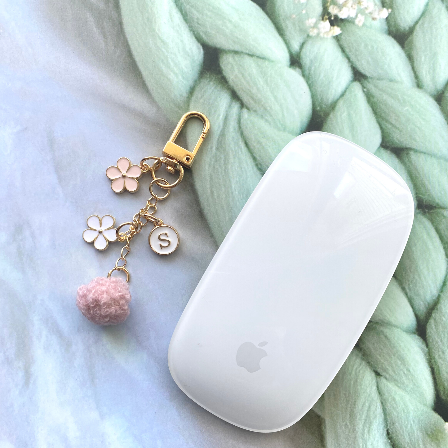 Floral initial keychain with pink pom charm and gold hardware, perfect for personalized gifts.