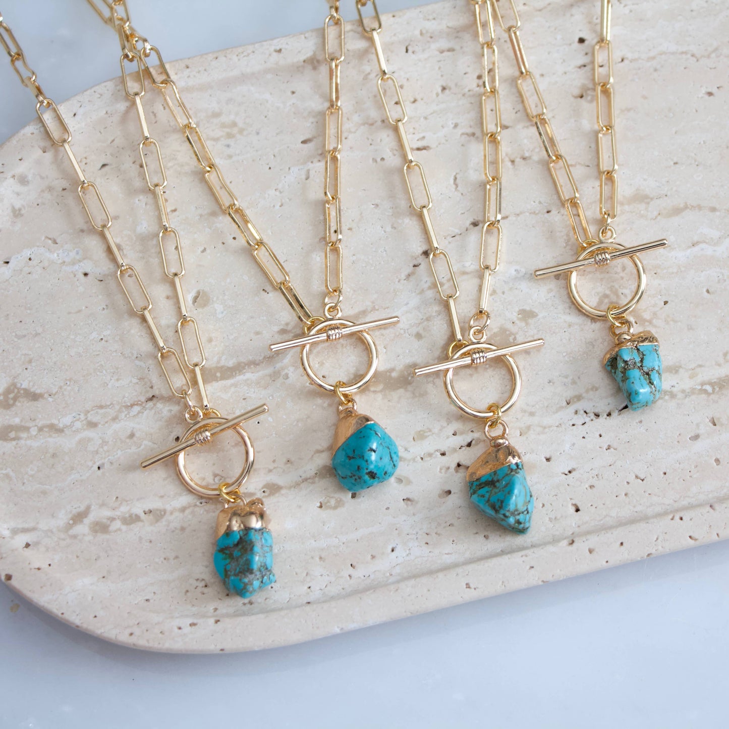 Gold paperclip chain necklace with a turquoise nugget pendant and a toggle clasp.