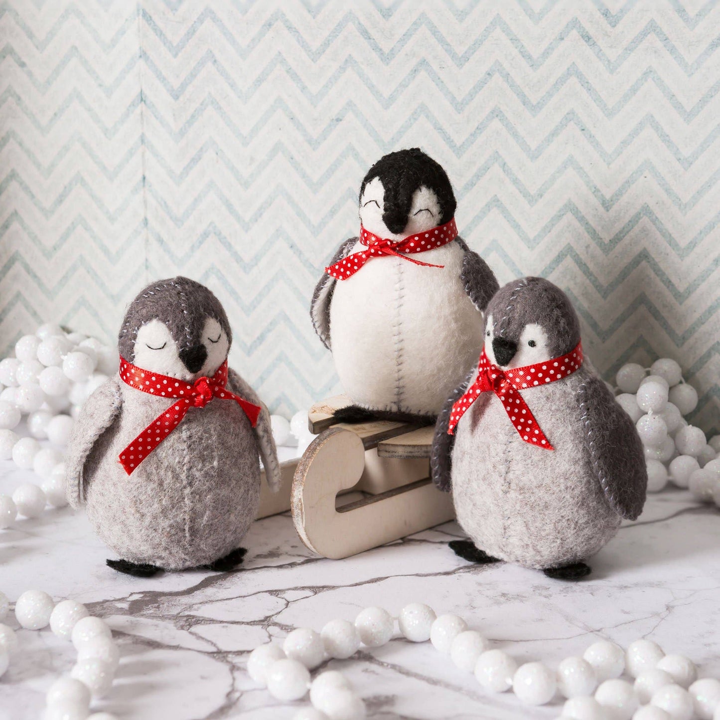 Three handmade felt baby penguins with red polka dot scarves