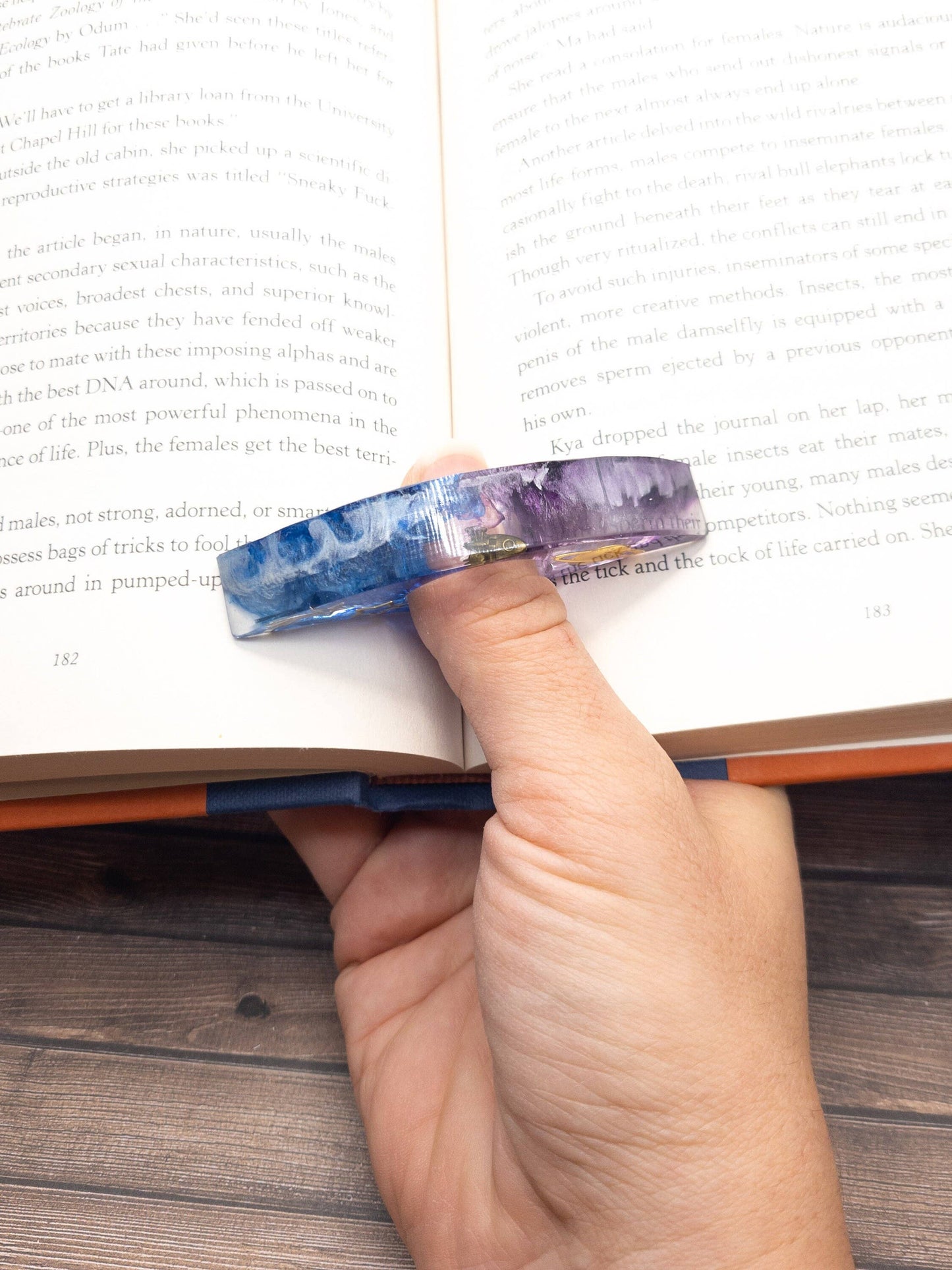 A purple and blue resin book page holder with a galaxy-inspired design keeps your place effortlessly.