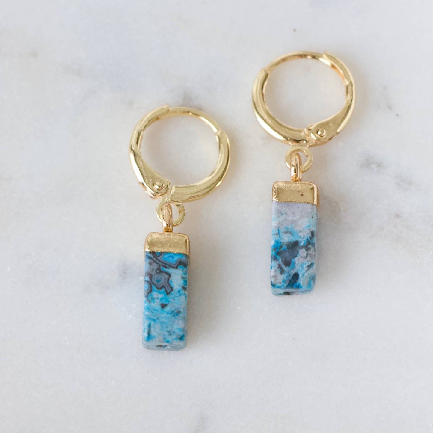 Turquoise rectangle stone huggie earrings with gold hoops and dangling charms.