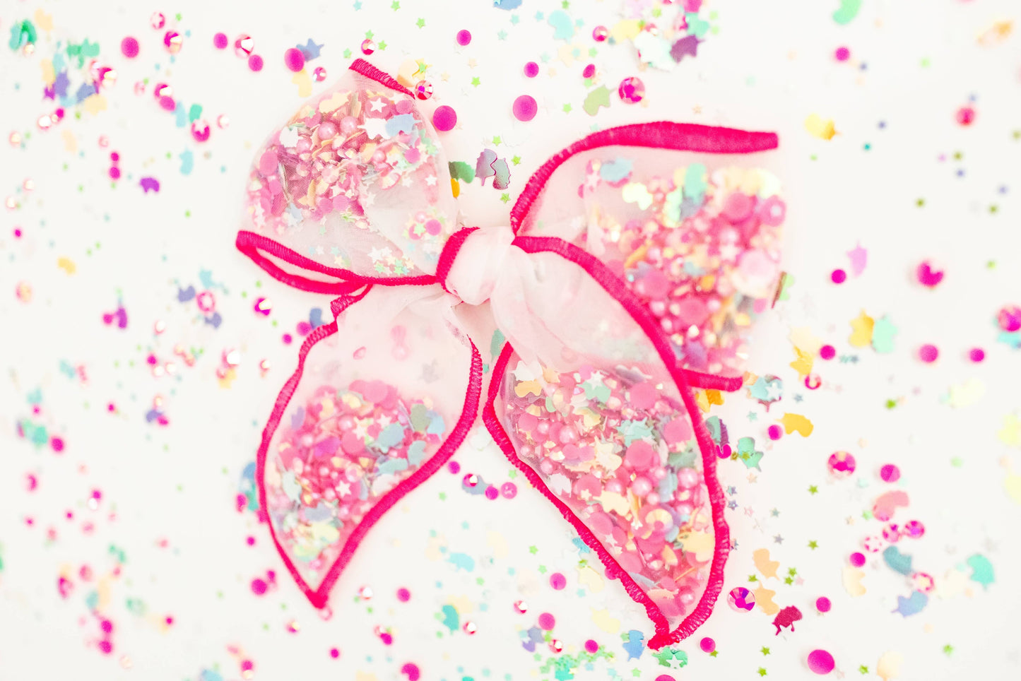 Pink mesh shaker bow filled with unicorn confetti, perfect for adding a magical touch to any hairstyle.