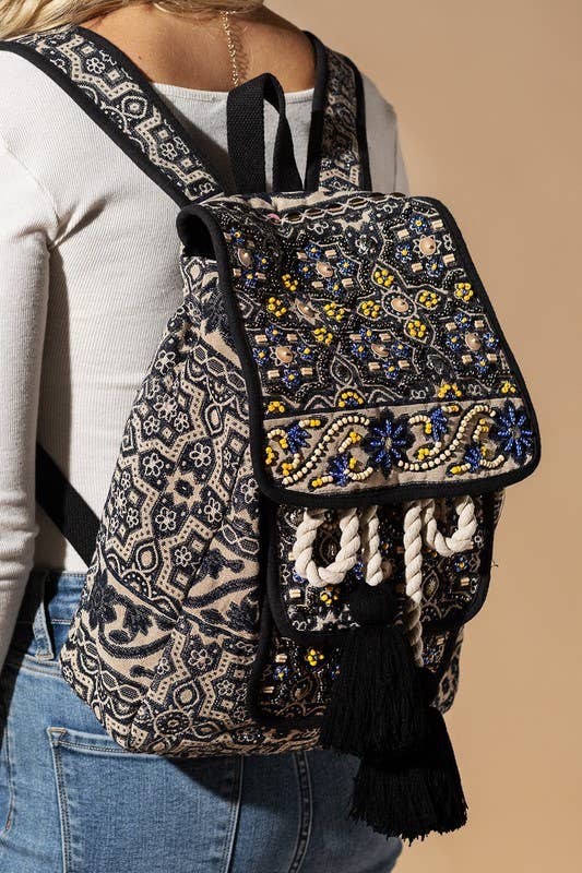 Hand-beaded bohemian backpack with intricate moon flower design, featuring tassels and rope accents.