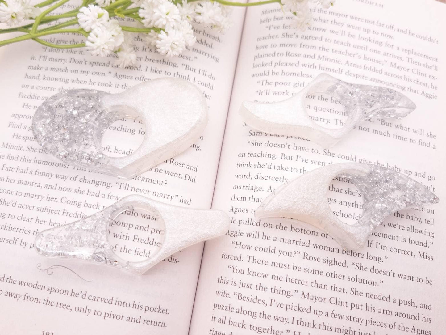 White and silver thumb book holders on open book with flowers