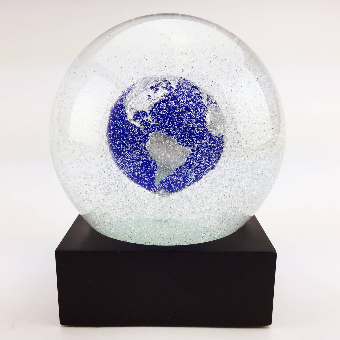 A handcrafted snow globe featuring a blue marble Earth design on a black base, perfect for unique gifts.