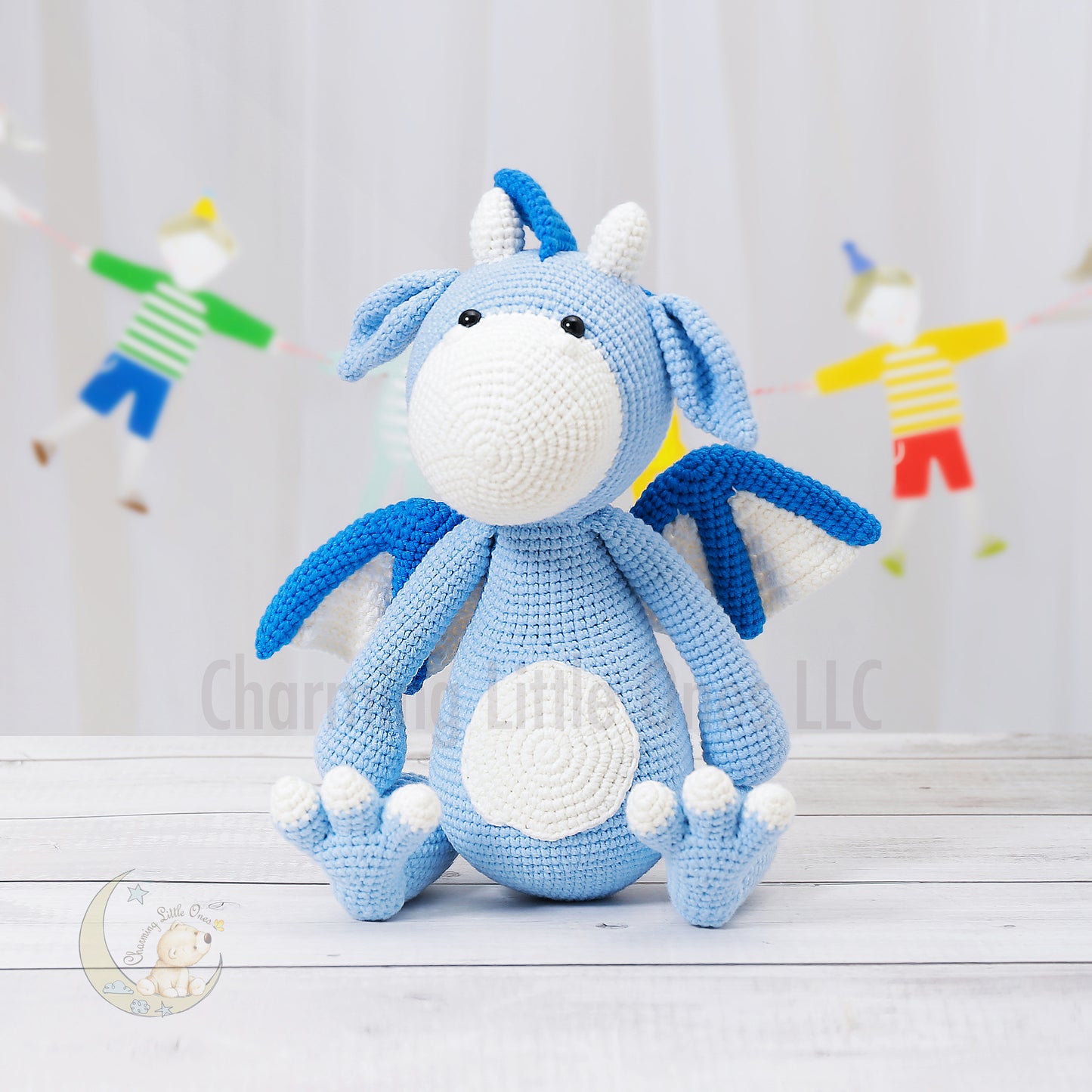 Handmade crochet dragon in soft blue with white accents, featuring wings and a playful design.
