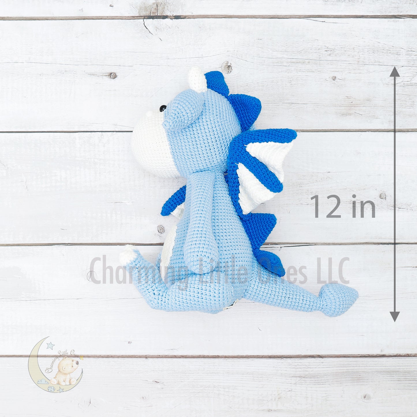 A handmade crochet dragon toy in blue and white, 12 inches tall.