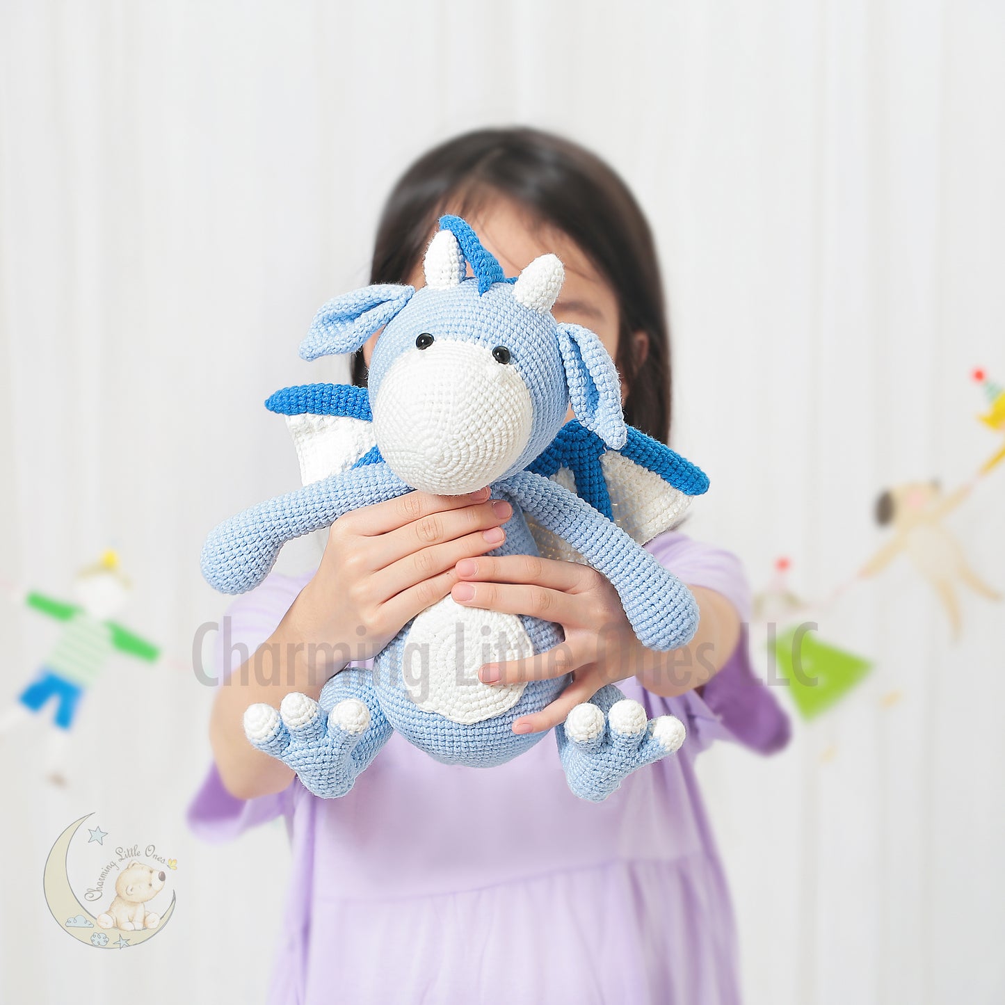 A handmade crochet dragon toy in blue and white, 12 inches tall.