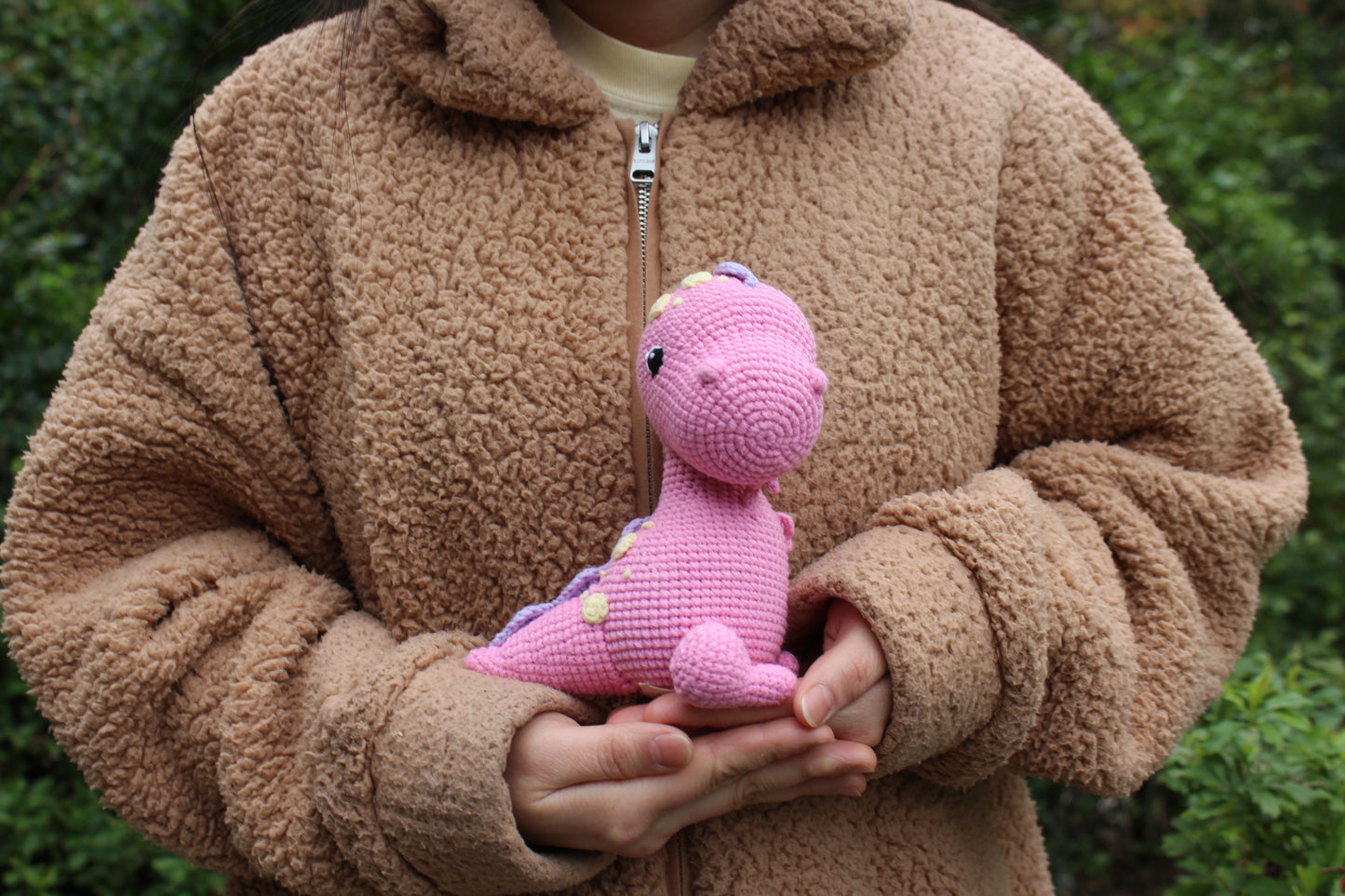 Adorable pink crocheted baby T-Rex with yellow spots and a purple crest, perfect for little dinosaur fans.