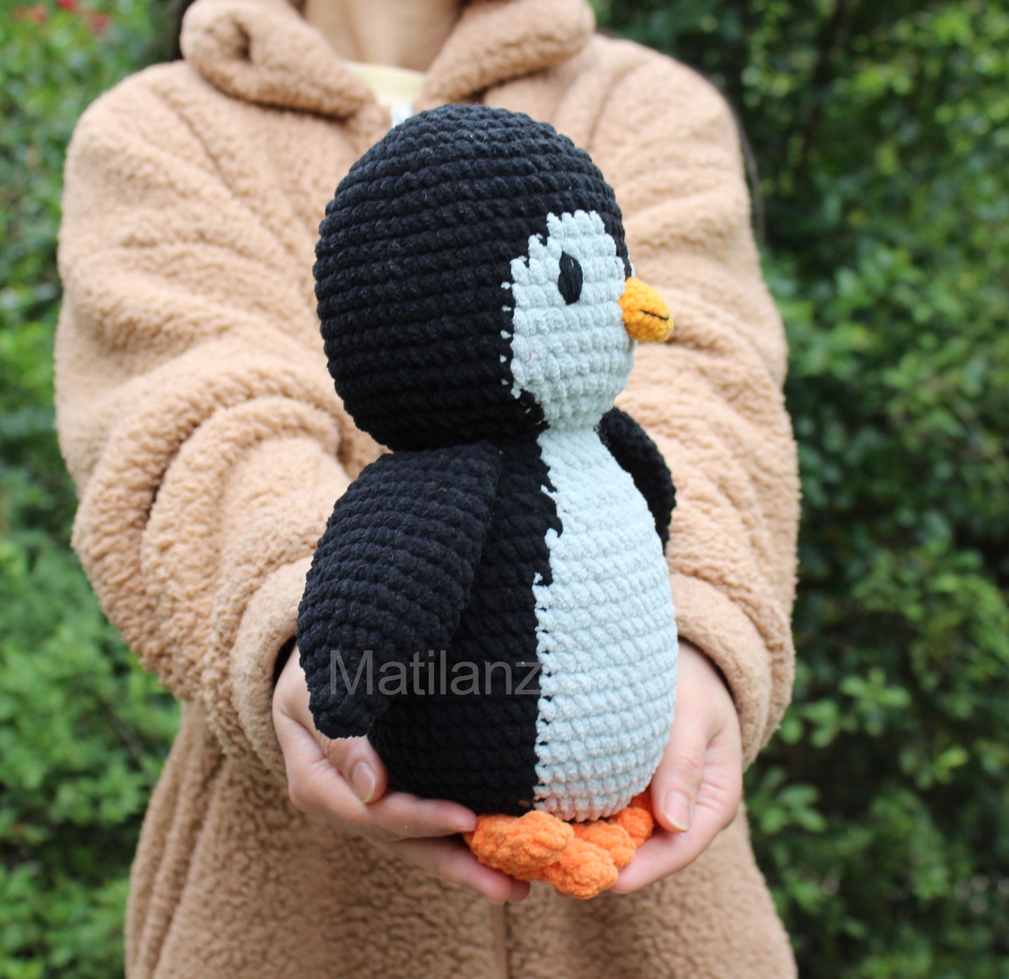 A cozy 10-inch crochet penguin plush with black, white, gray, and orange accents.