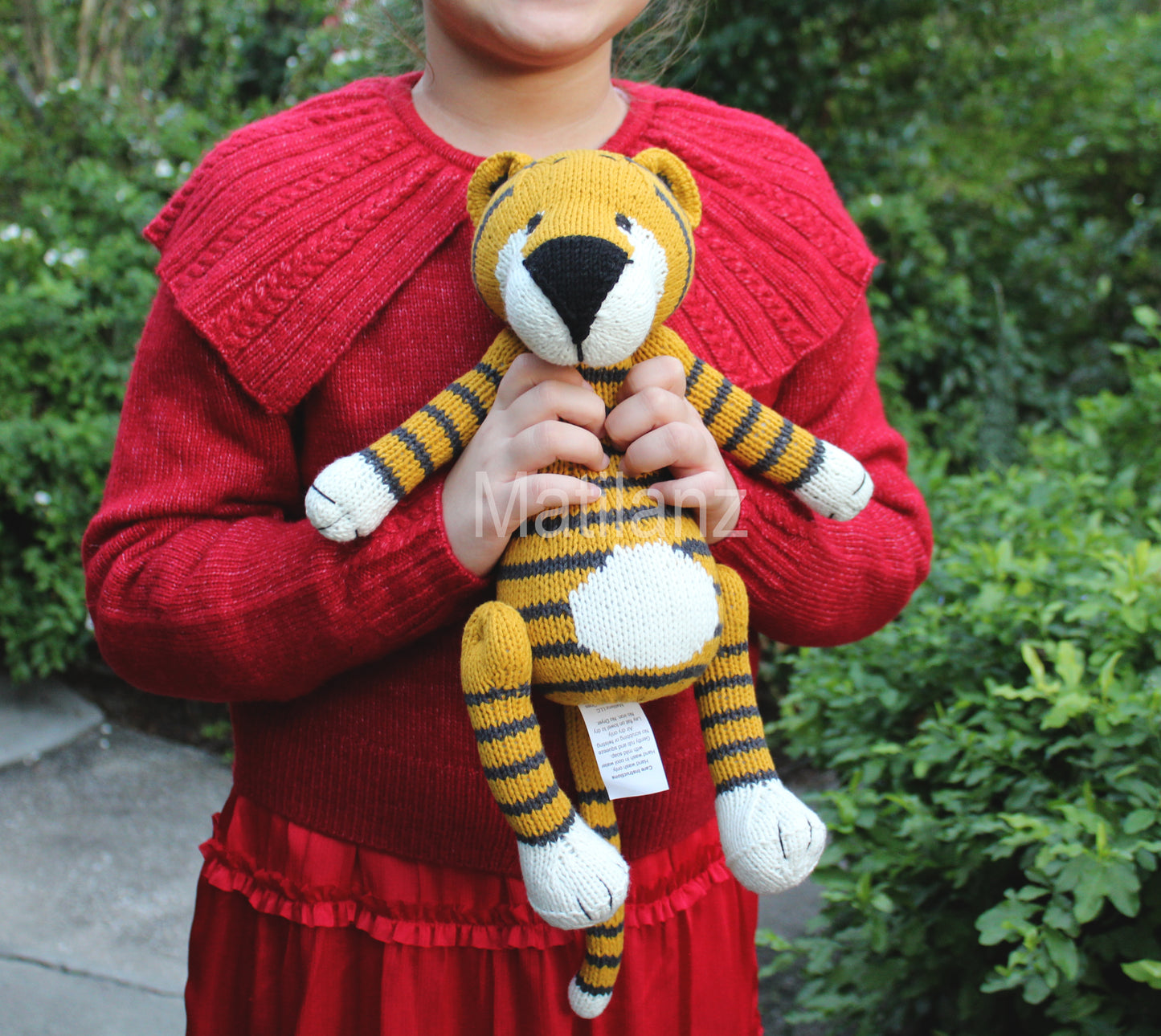 Handmade knitted tiger in turmeric yellow with black stripes and white accents, 14 inches tall.