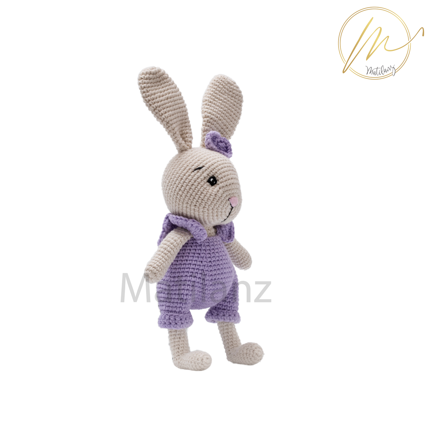 A handmade crochet rabbit wearing a purple overalls, standing upright.