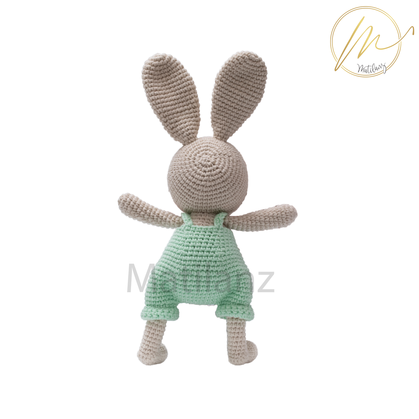 A handmade crochet rabbit wearing a mint green overalls, standing upright.