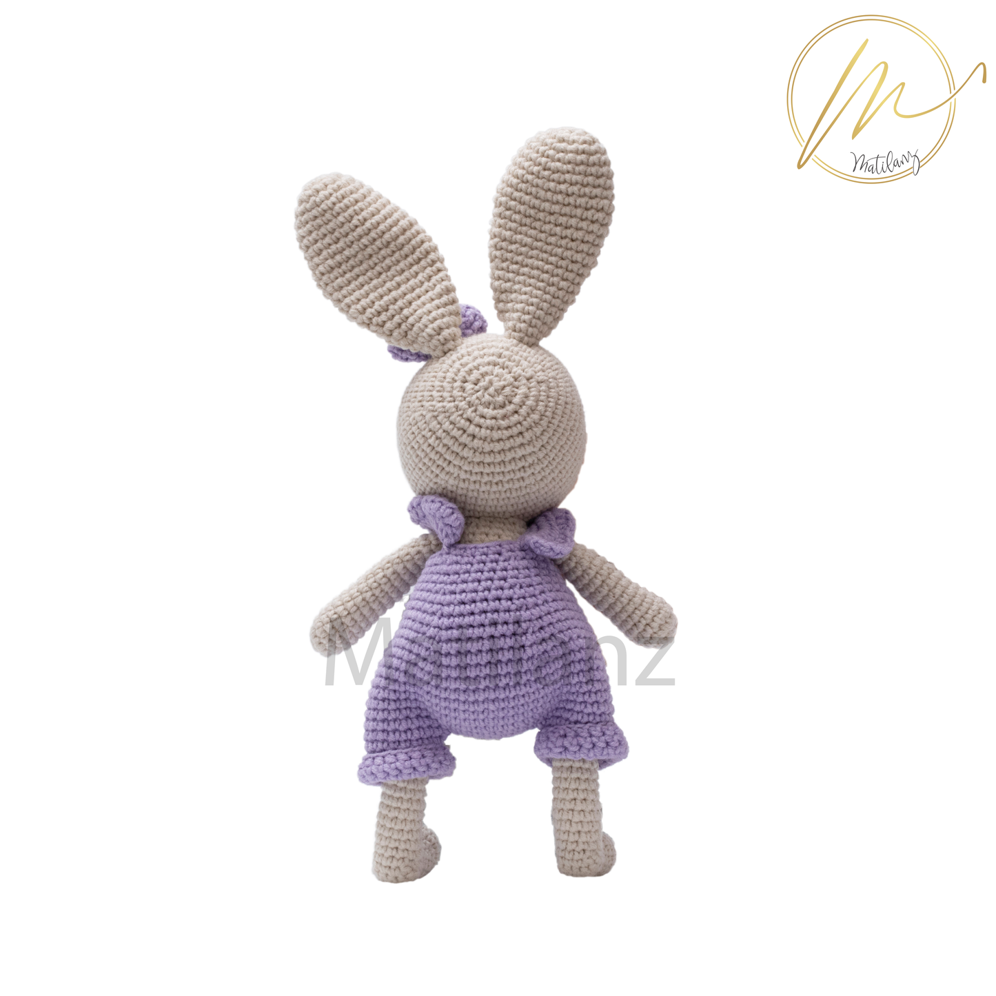A handmade crochet rabbit wearing a purple overalls, standing upright.