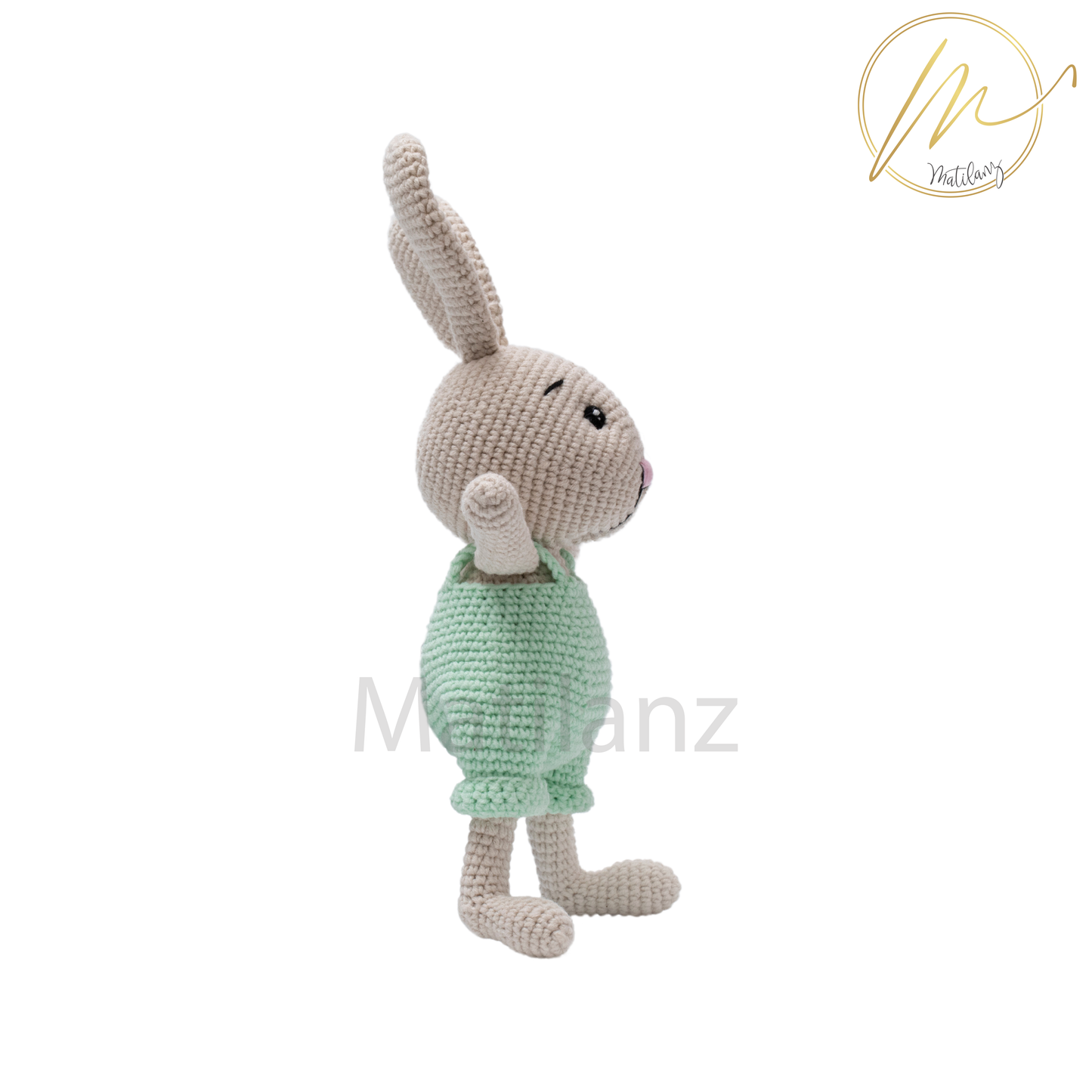 Handmade crochet rabbit in mint green overalls, standing upright with a soft, cozy texture.