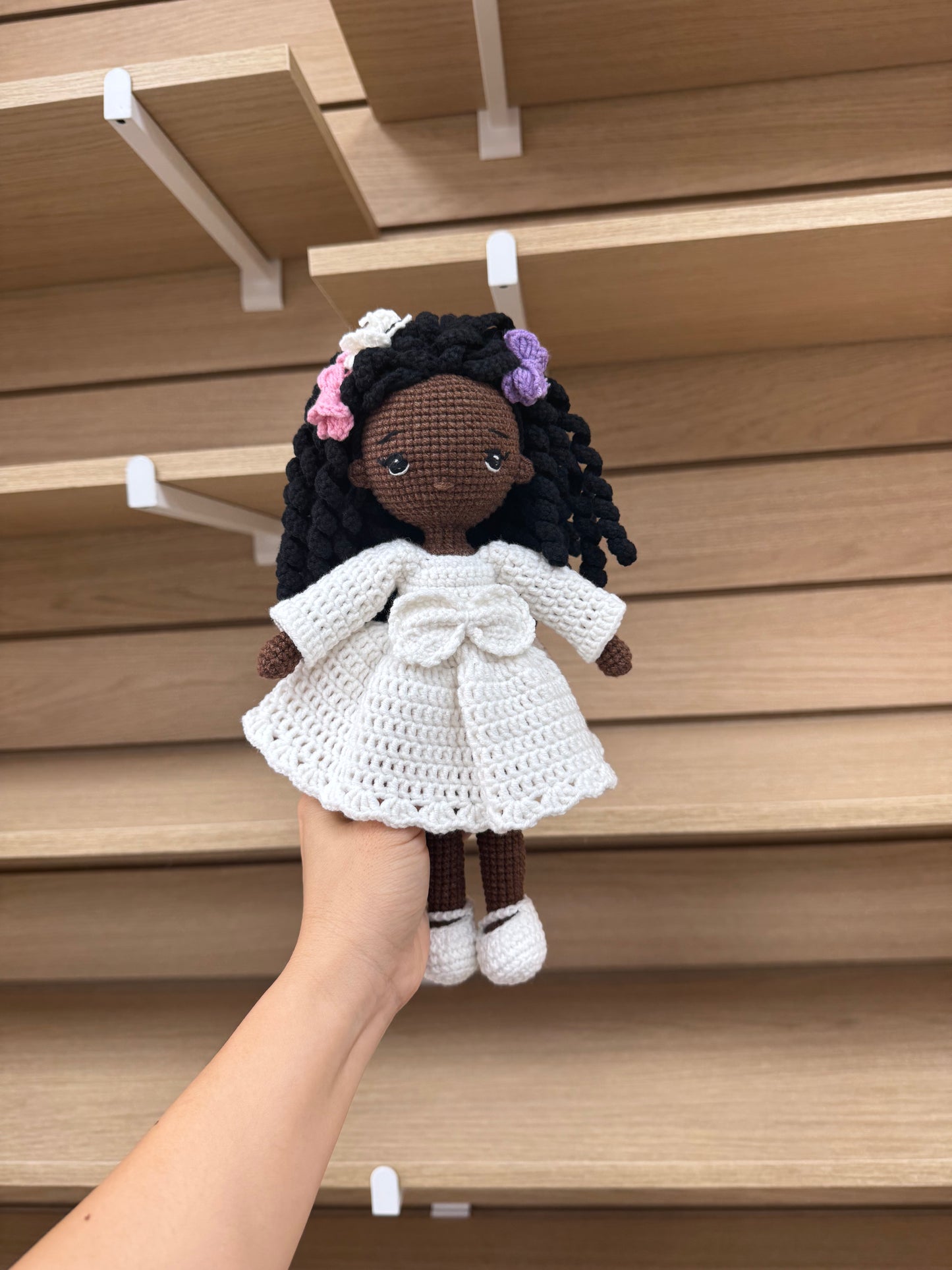Handmade crochet African American doll with braided hair, colorful flowers, and a white dress.