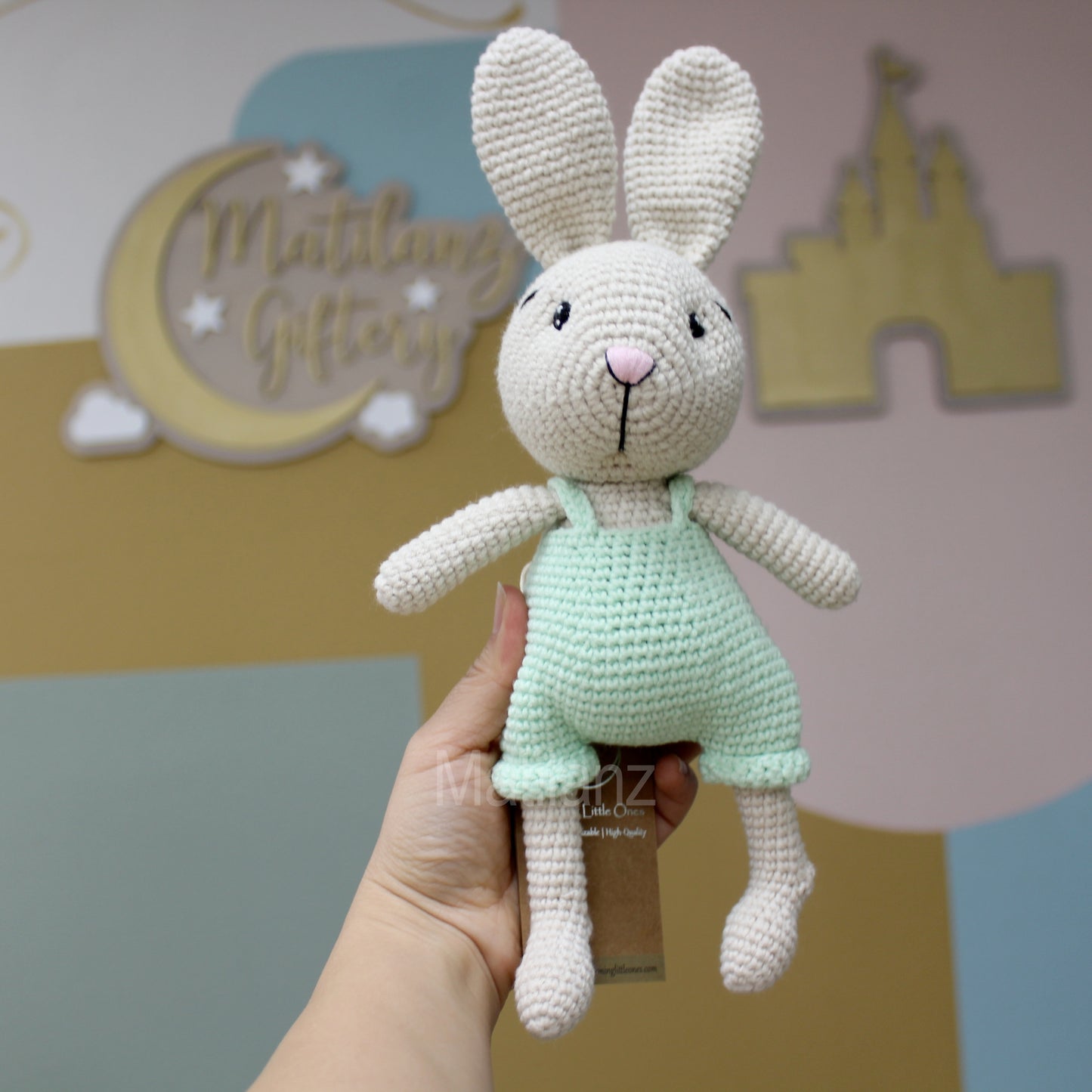 A handmade crochet Easter bunny in cream with a mint green dress, 10 inches tall.