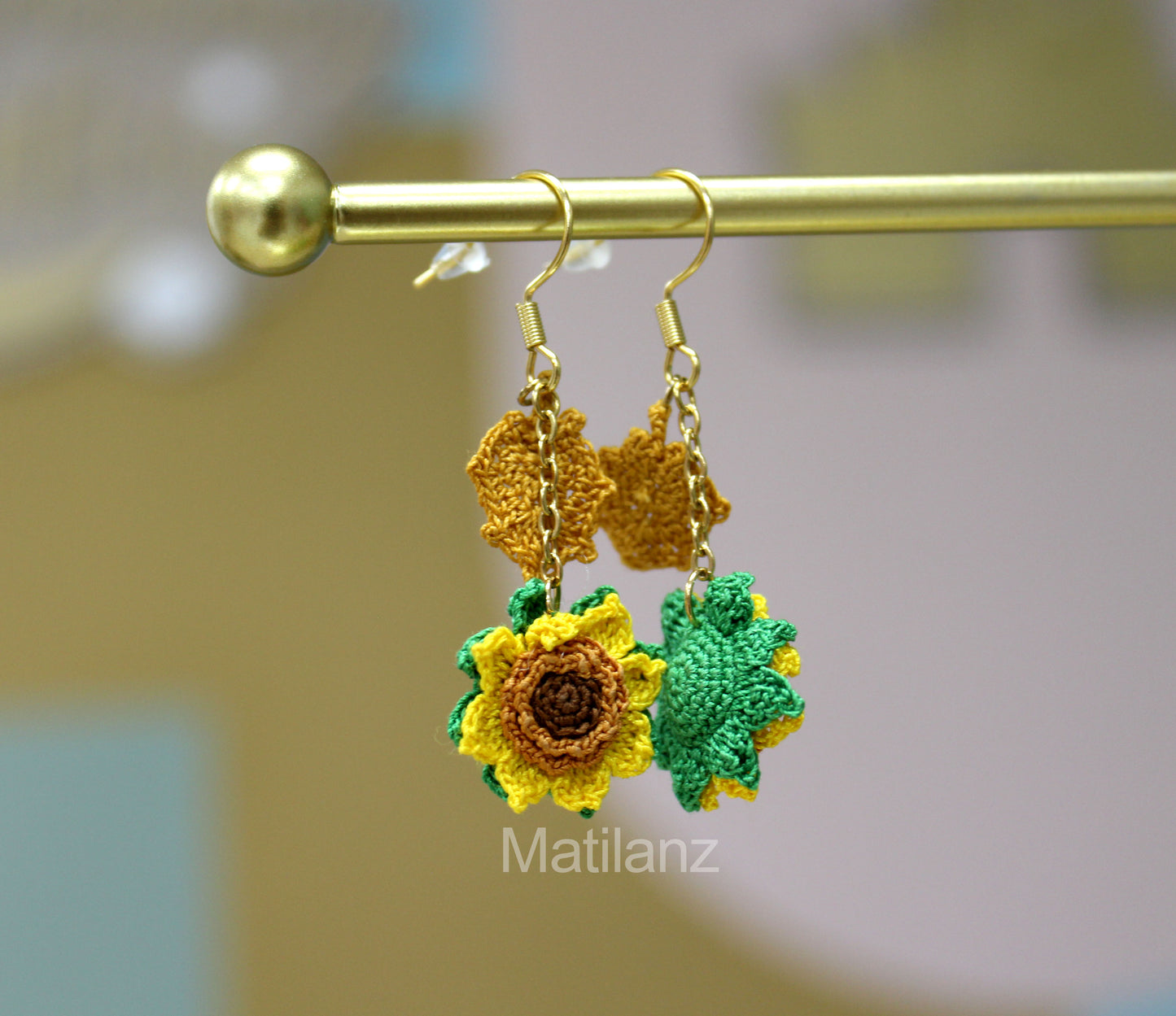 Handmade crochet earrings featuring yellow sunflowers with green leaves and gold hooks.
