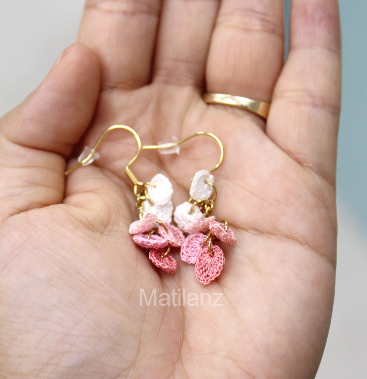 Crochet handmade earrings with pink and white heart-shaped charms, gold hooks.
