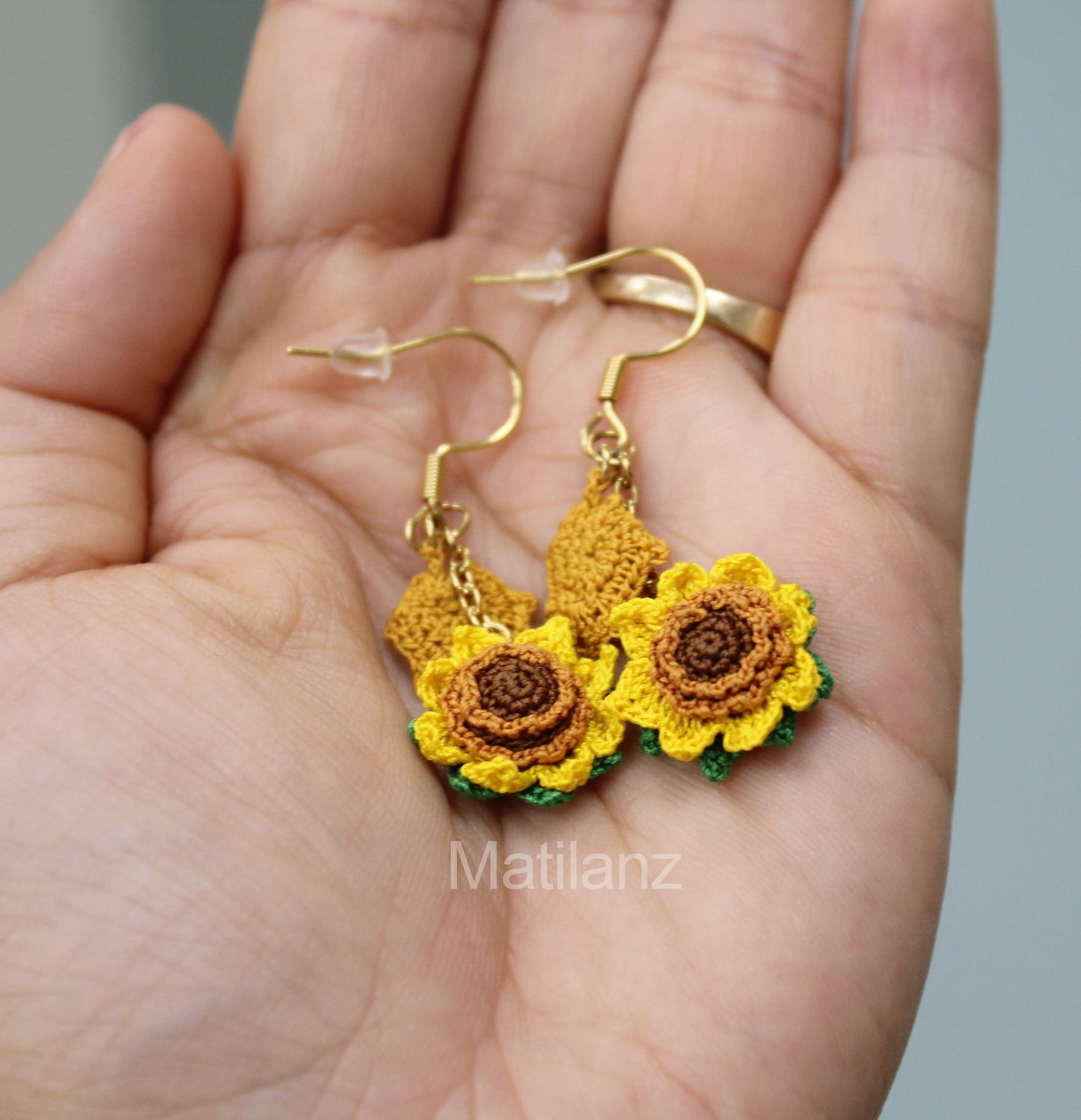 Crochet handmade sunflower earrings with gold hooks, featuring vibrant yellow and green details.