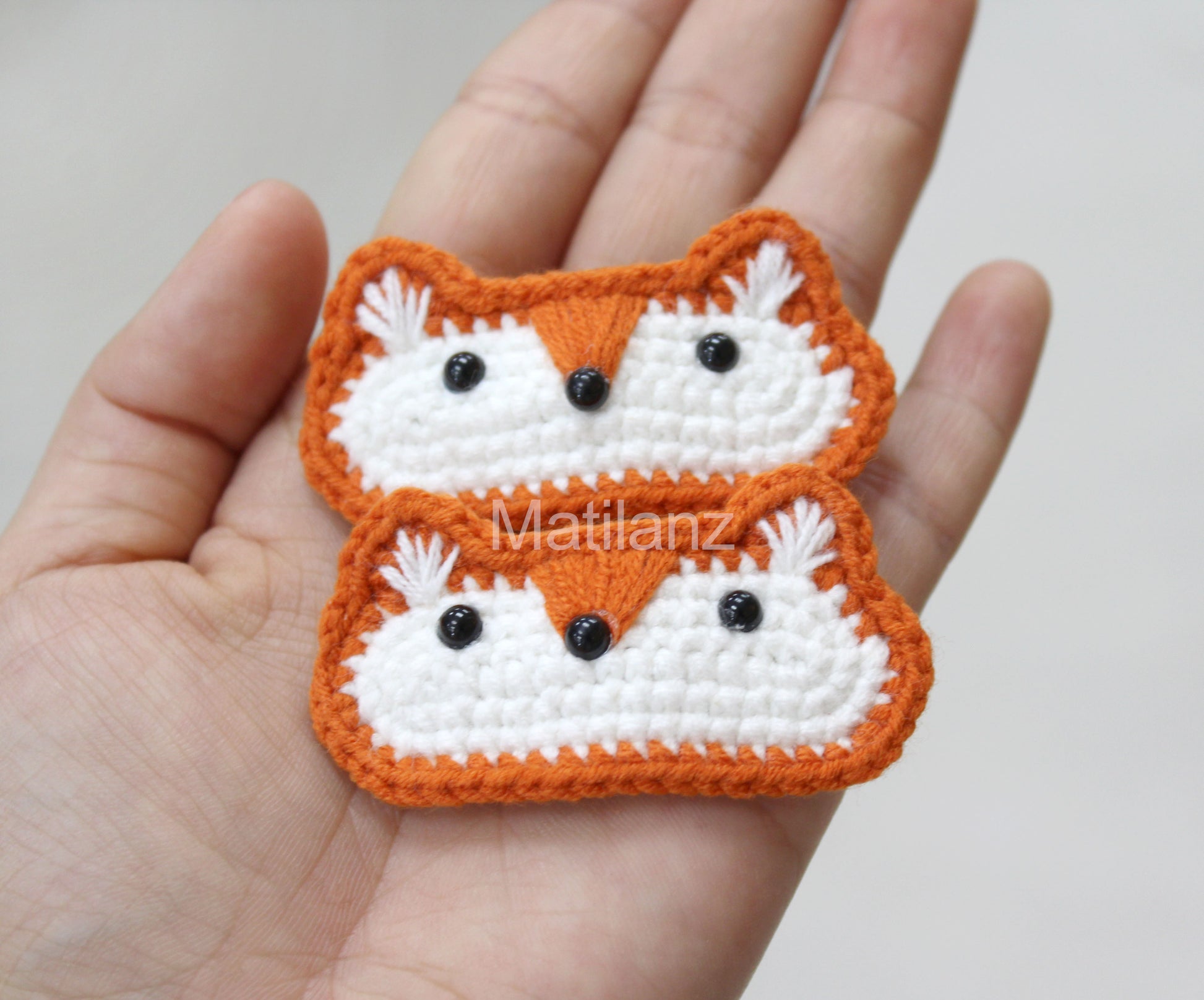 Crochet fox hair clips in orange and white, featuring black bead eyes and fluffy white ears.