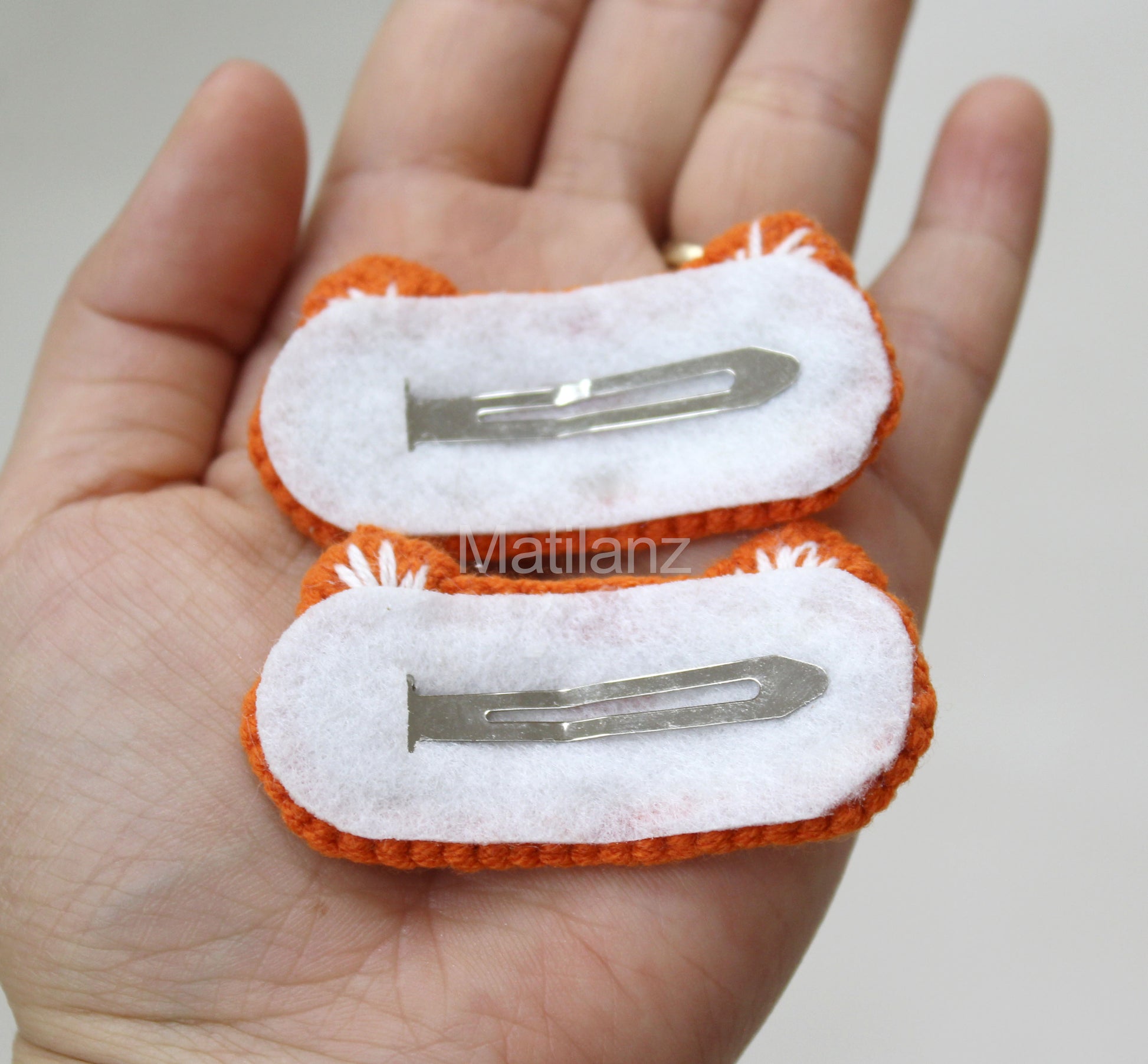 Crochet fox hair clips in orange and white, handmade with fluffy tails and metal clips.