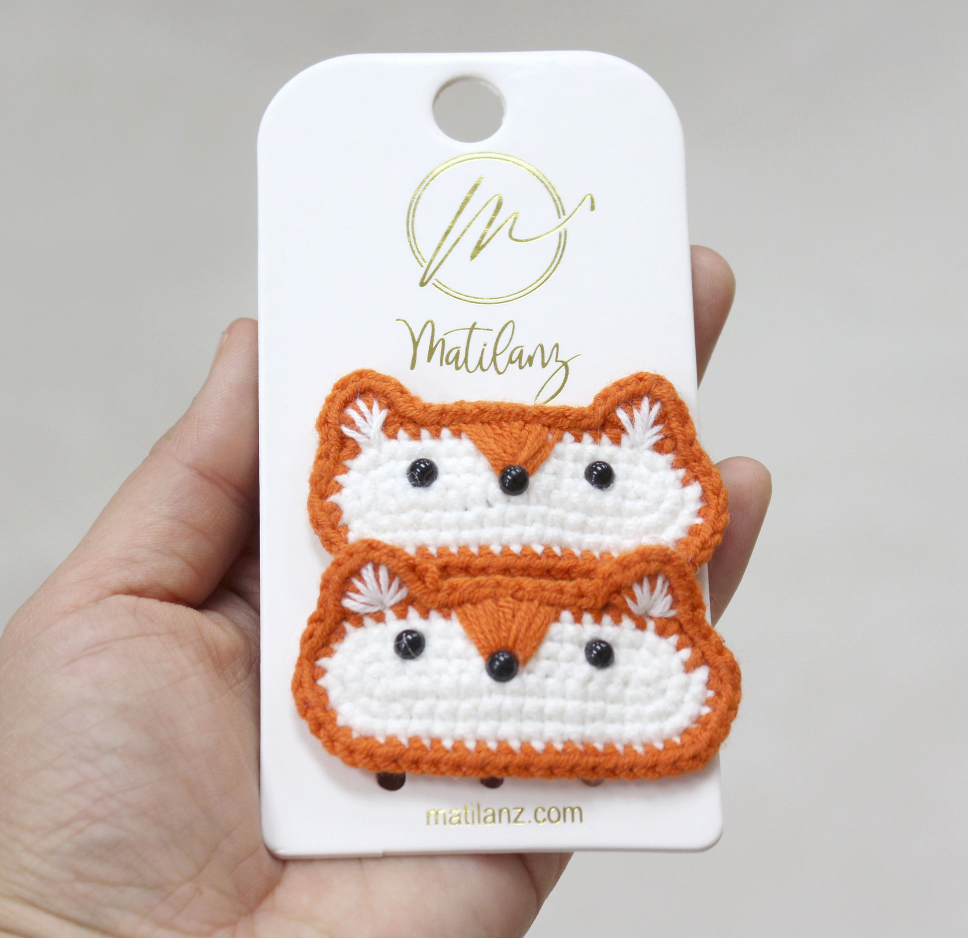 Crochet fox hair clips in orange and white, featuring cute black eyes and fluffy ears.