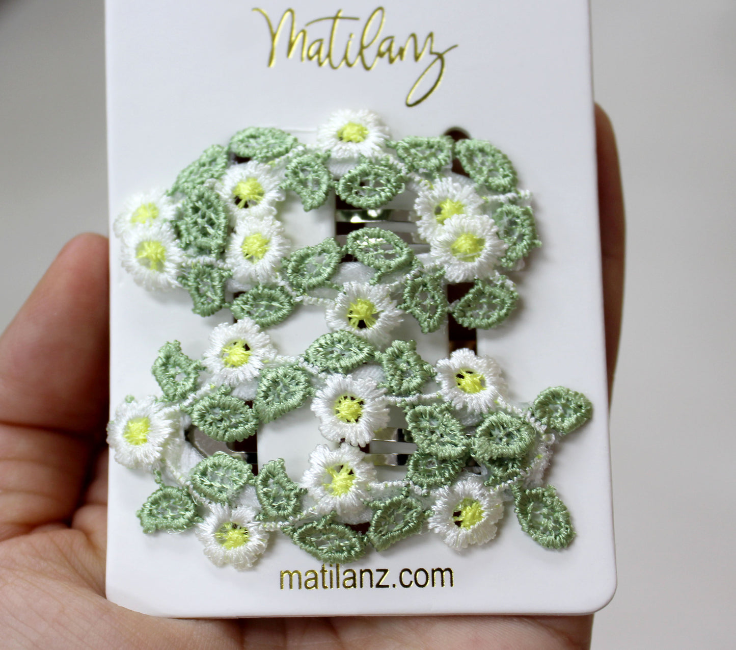Charming floral embroidery hair clip with white and green flowers, perfect for styling.