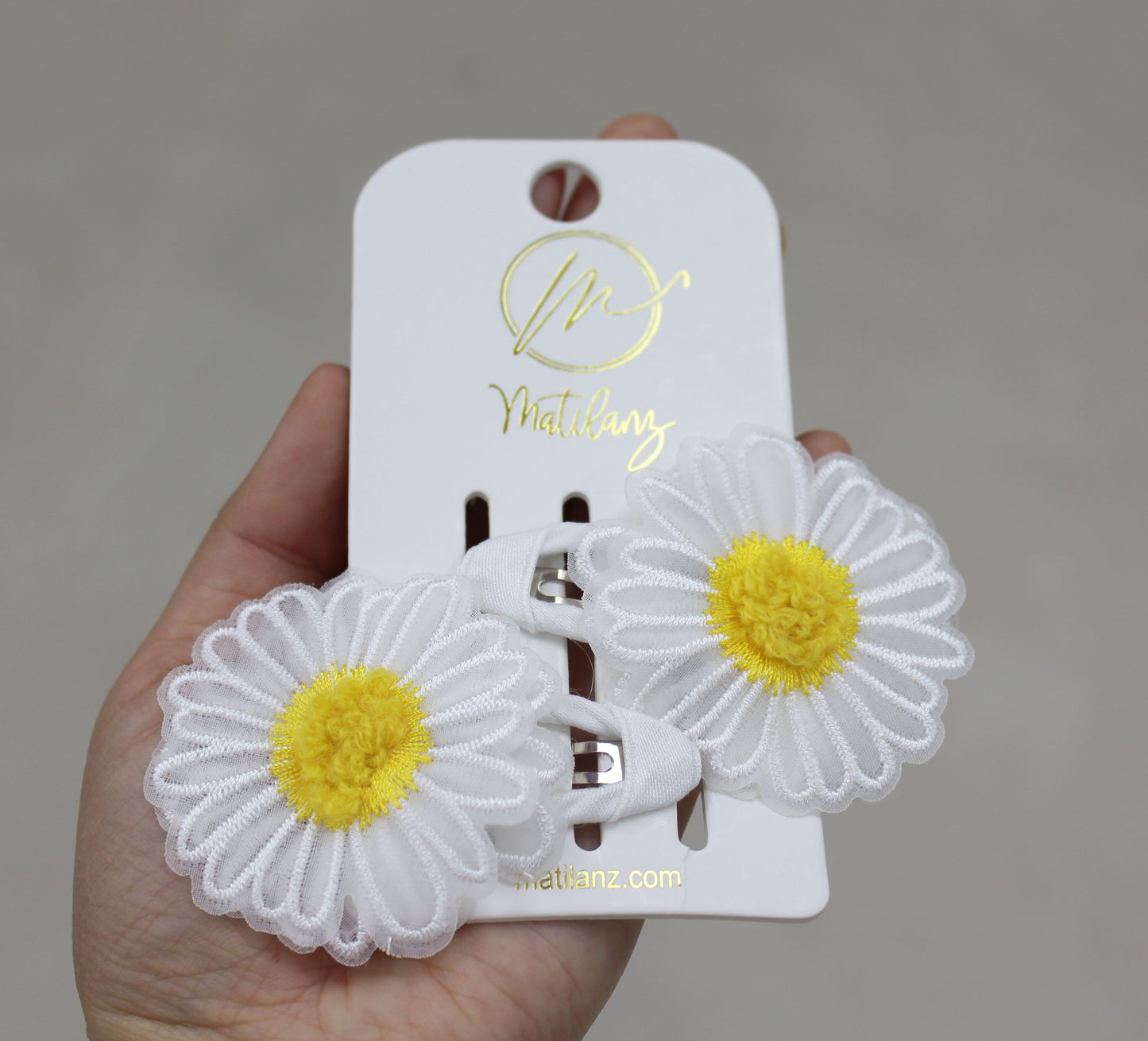 Two delicate flower hair clips with white embroidered daisies and yellow centers, set in white clips.