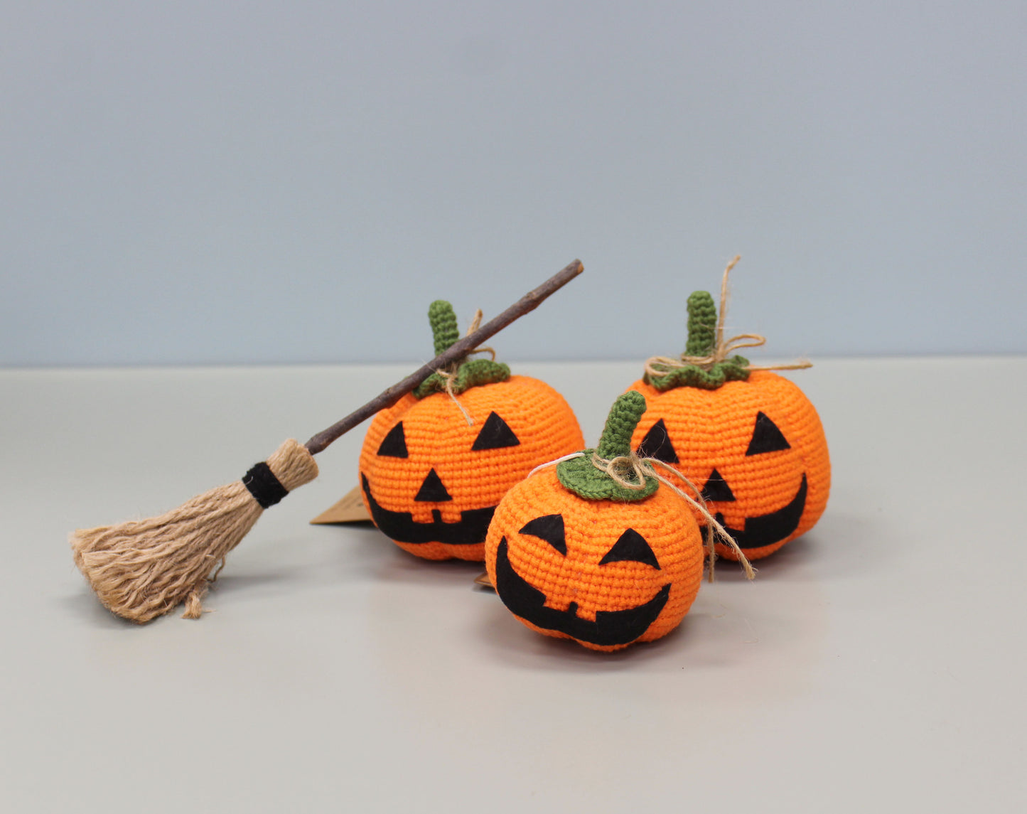 Handmade crochet plush orange pumpkin with a green stem and black jack-o'-lantern face.