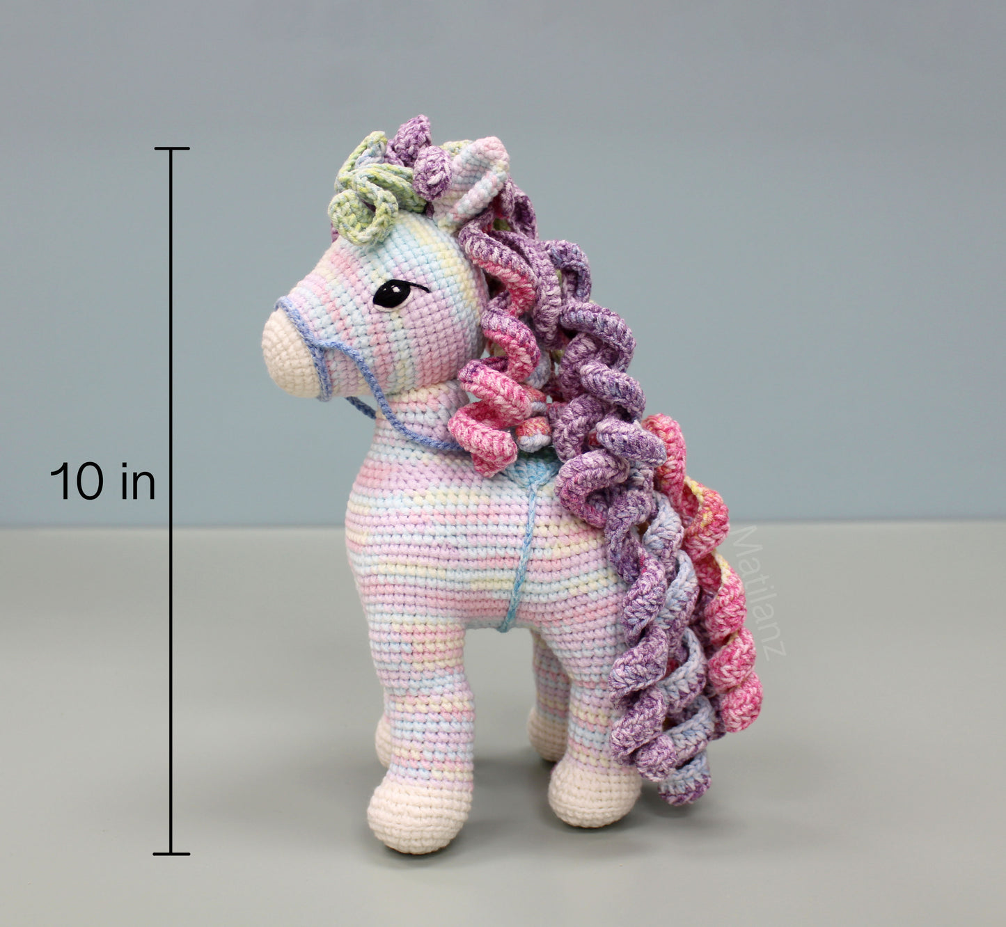 Handmade 10" crochet rainbow horse with pastel colors, curly mane, and large embroidered eyes.